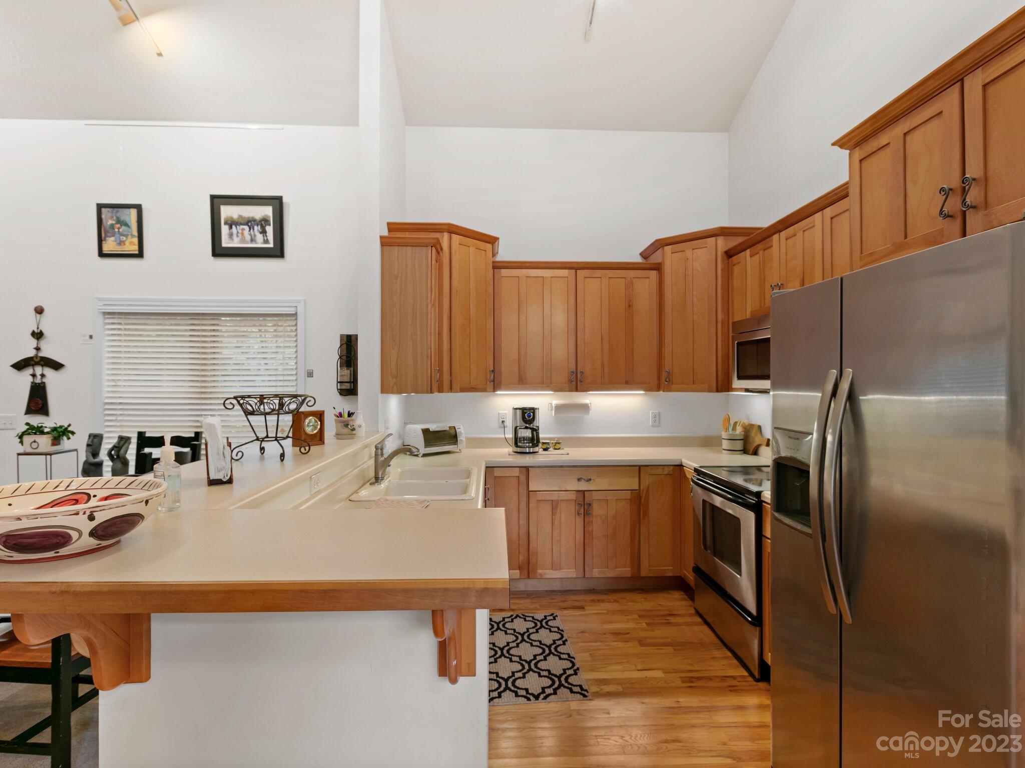 Kitchen with warm wood cabinetry, a large peninsula, and stainless steel appliances.