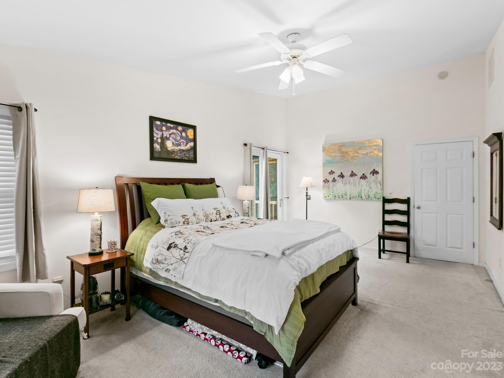 Furnished bedroom with a dark wood bed, green-and-white bedding, framed artwork, and ceiling fan.