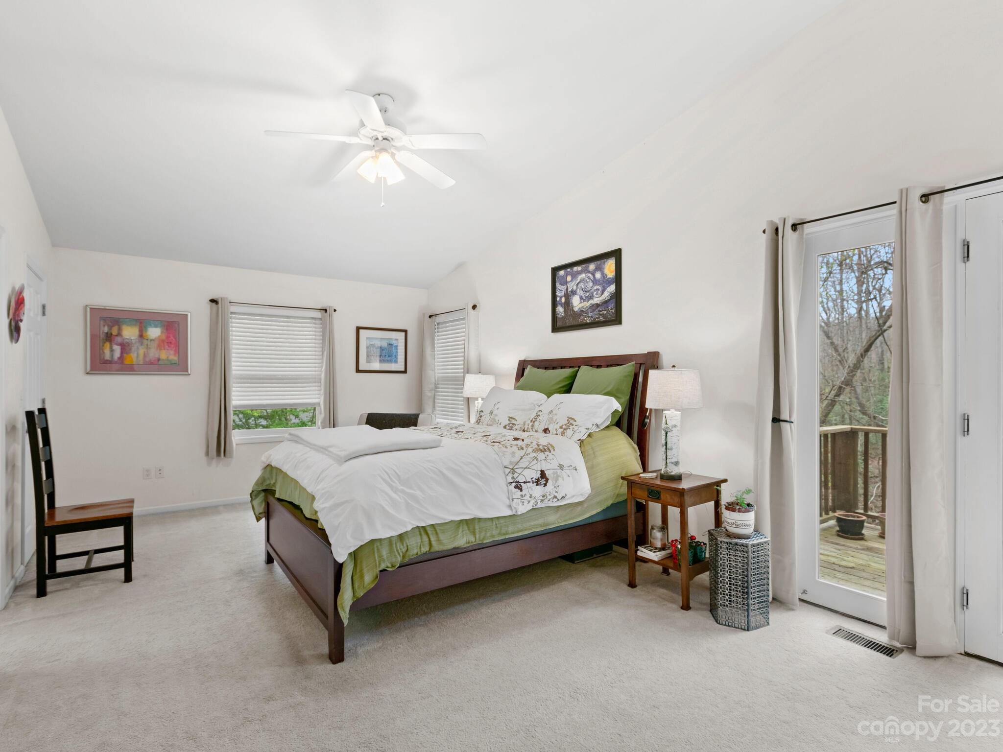 Furnished bedroom with a green-and-white bed and glass doors opening to a small deck.