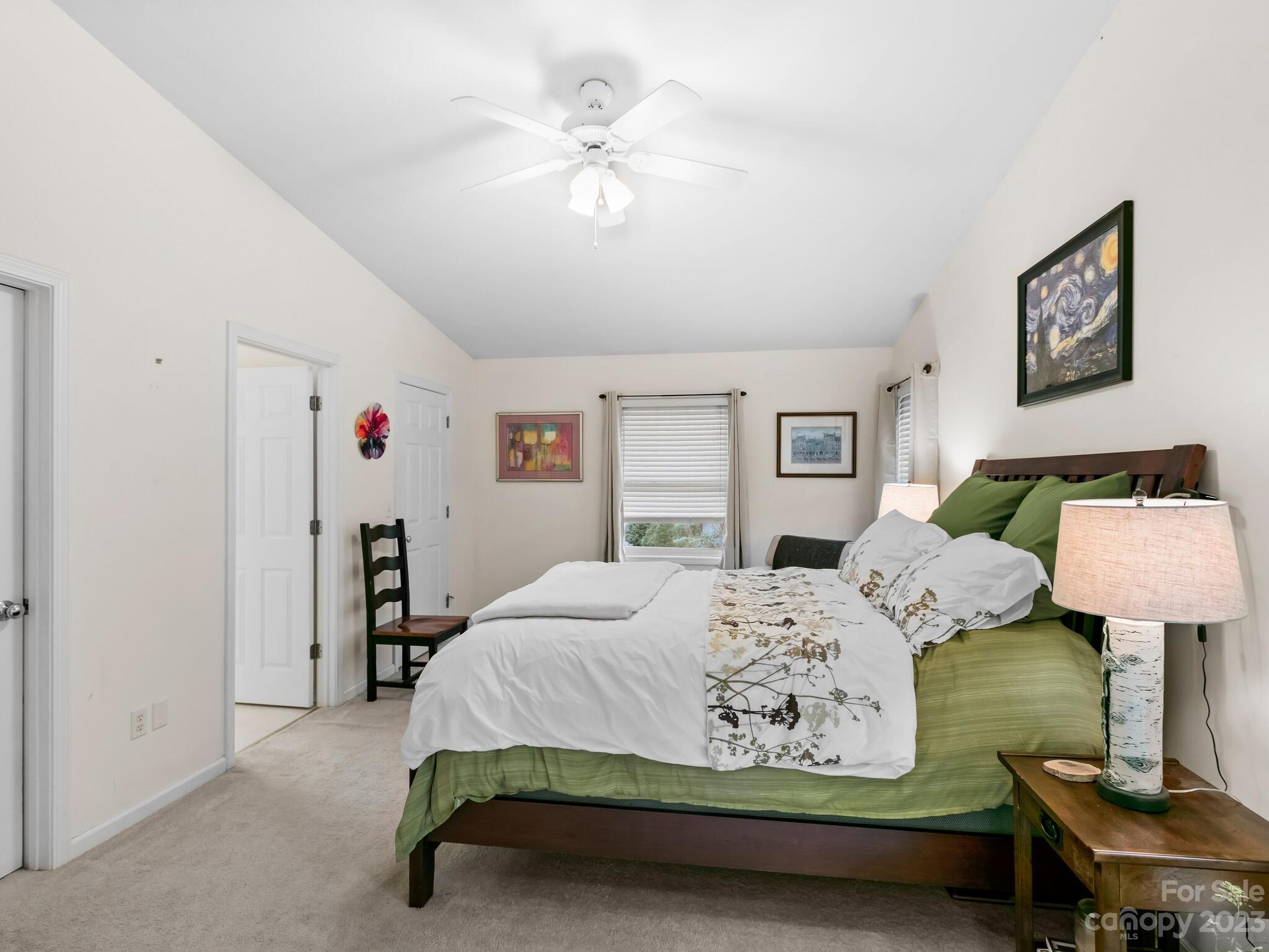 Furnished bedroom with green bedding, a vaulted ceiling, and a white ceiling fan.