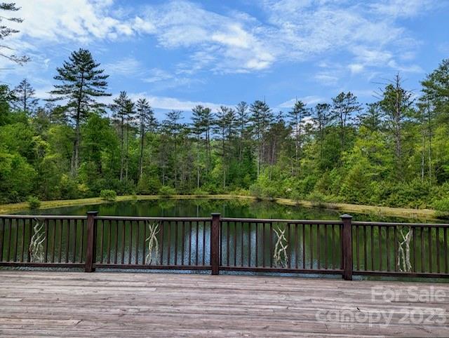 Wooden deck overlooking a pond bordered by dense green trees.