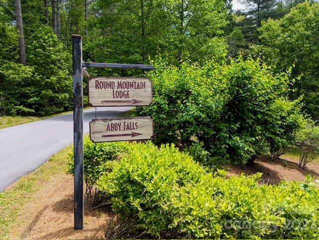 Wooden signs for Round Mountain Lodge and Abby Falls beside a wooded road.