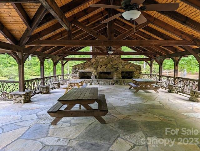 Covered timber pavilion with stone fireplace, flagstone floor, and picnic tables.