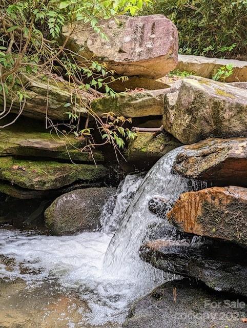 Small waterfall flowing over rocks into a shallow, foamy stream.