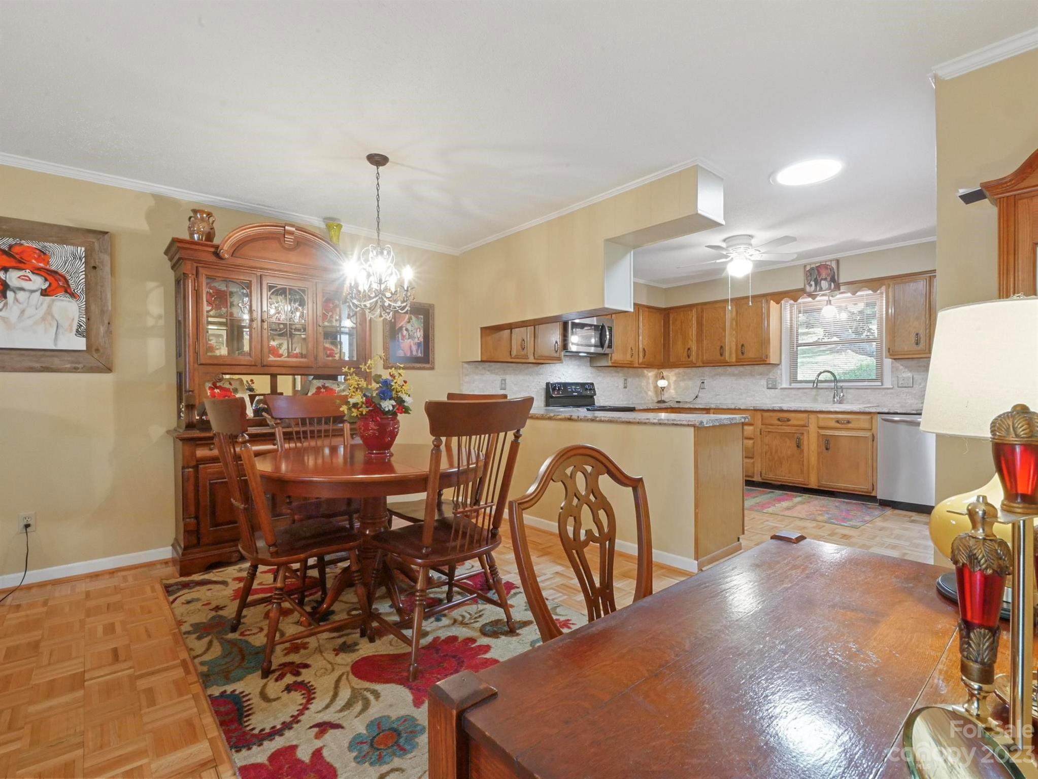 Dining area with a china cabinet and patterned rug beside a wood-cabinet kitchen.