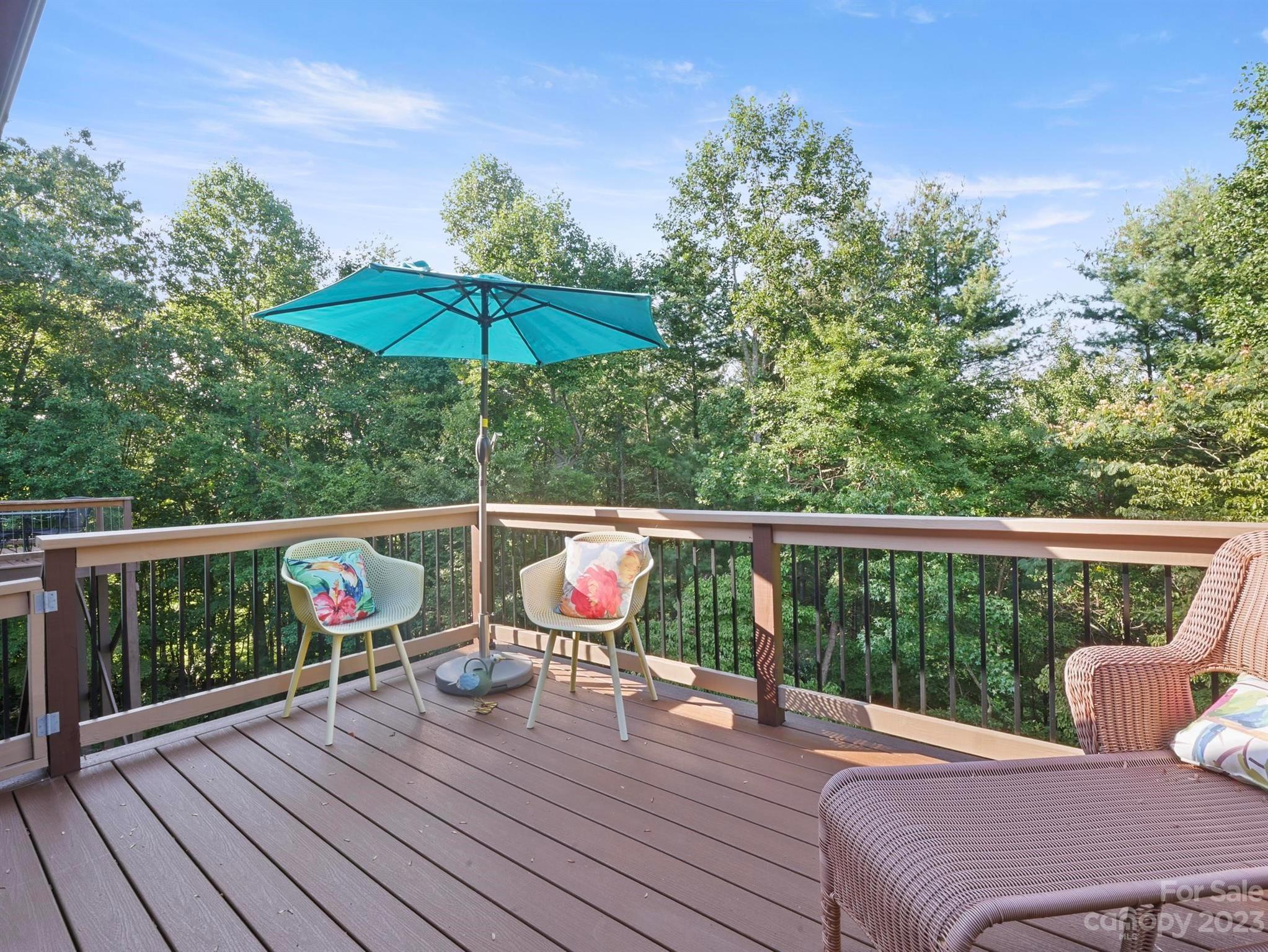 Wooded deck with wicker seating and a turquoise patio umbrella.