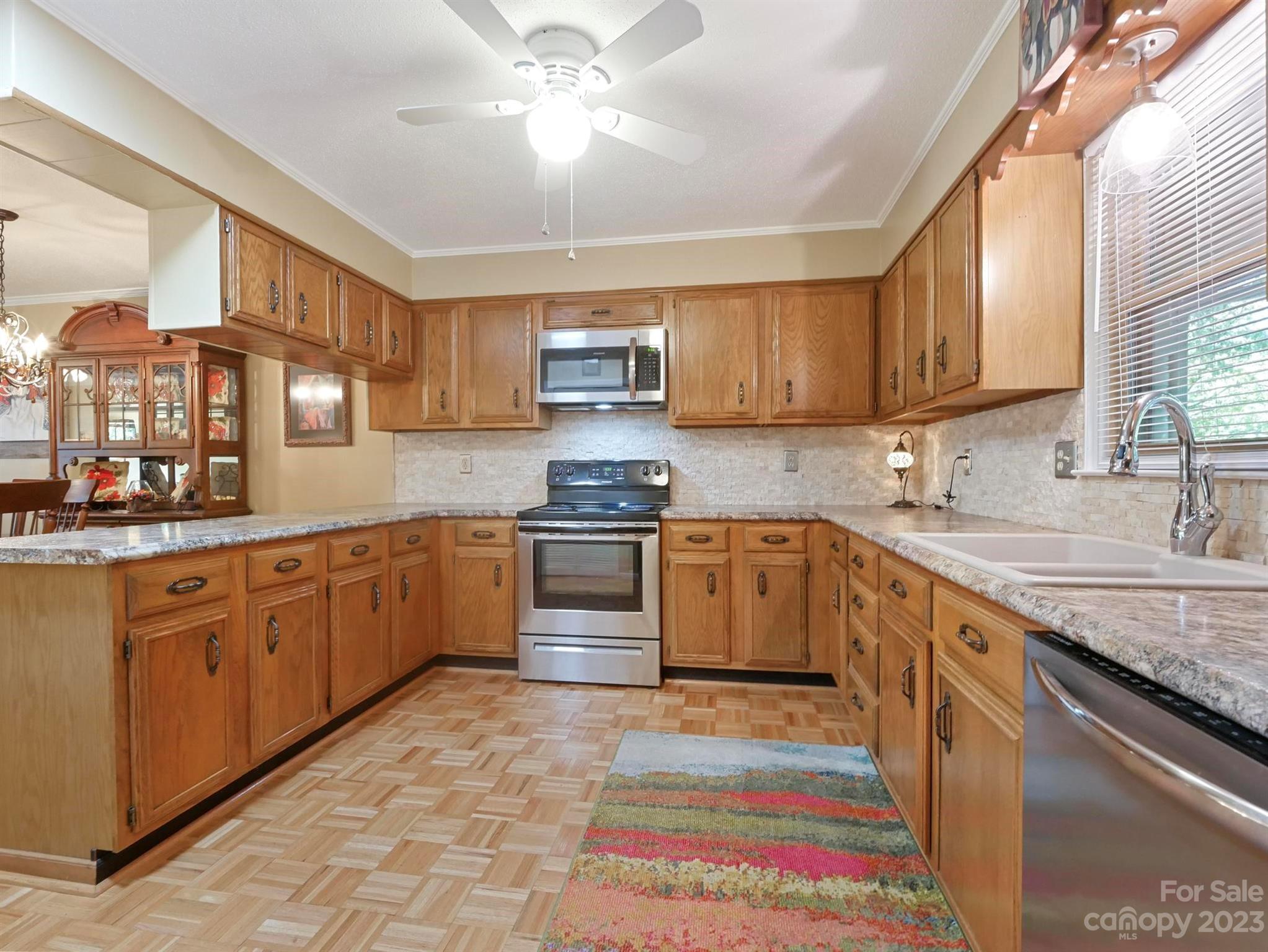 Kitchen with honey-colored wood cabinets, stainless steel appliances, and a colorful runner.