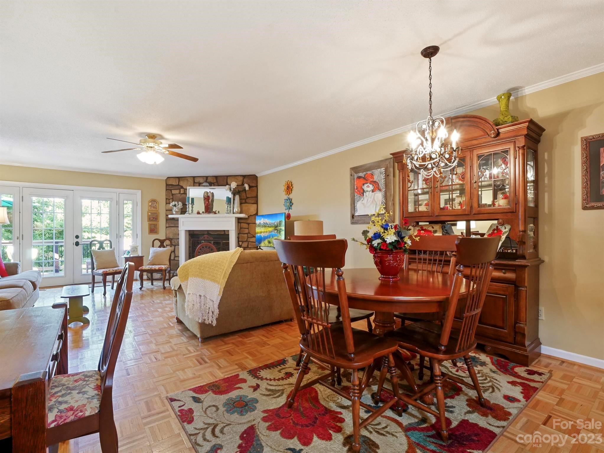 Dining and living room with a stone fireplace, wood dining set, and glass doors to the outdoors.