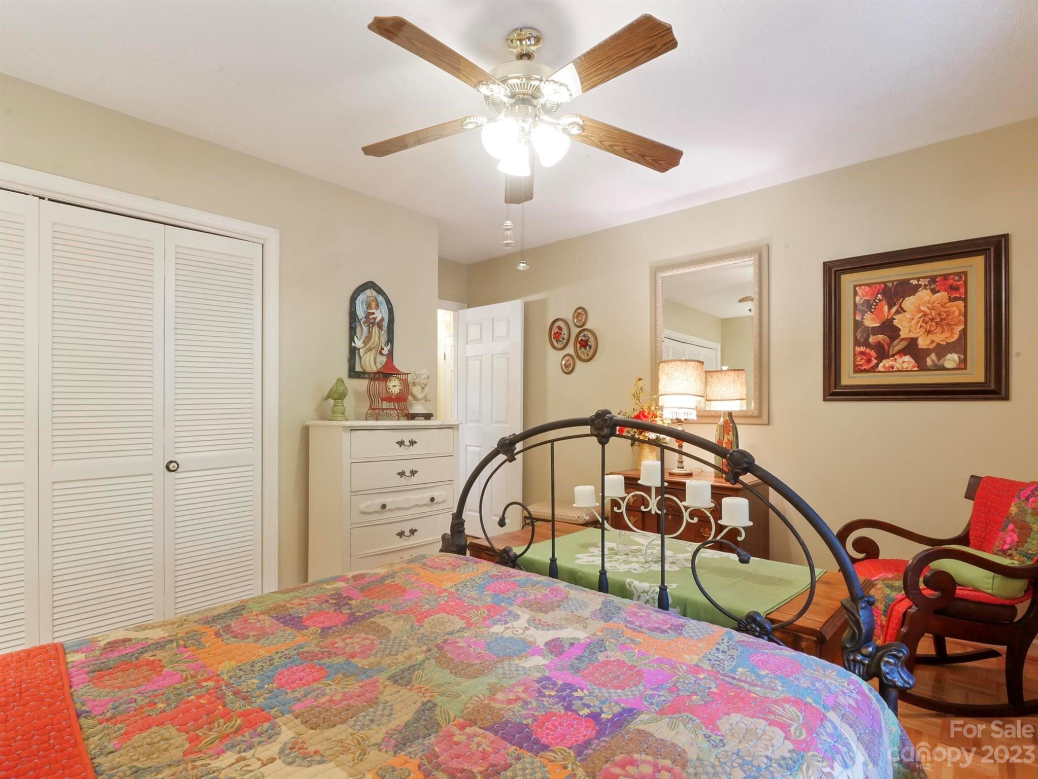 Bedroom with a black metal bed, colorful patchwork quilt, and ceiling fan.