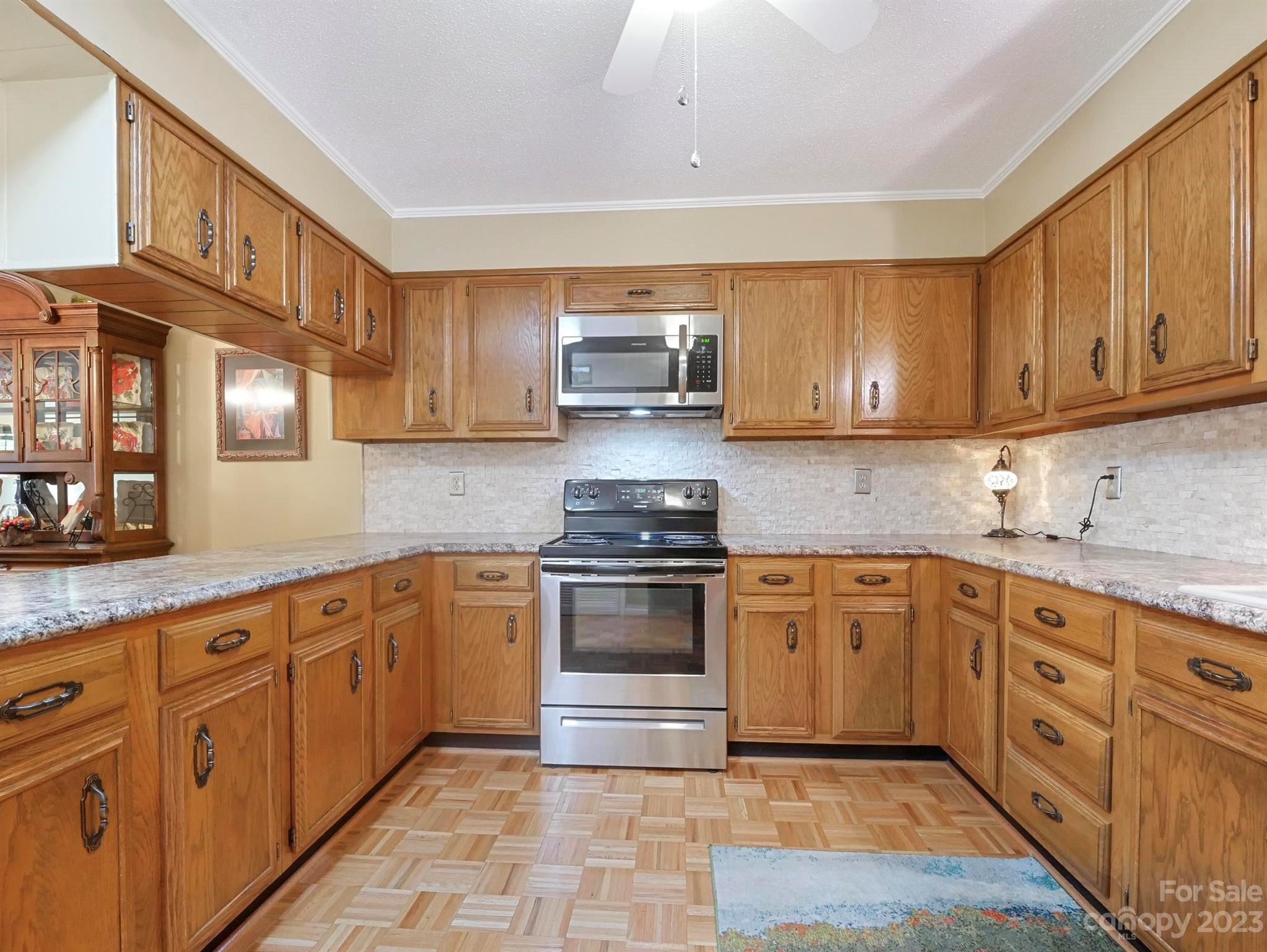 Kitchen with honey-colored wood cabinets, granite counters, and stainless-steel appliances.