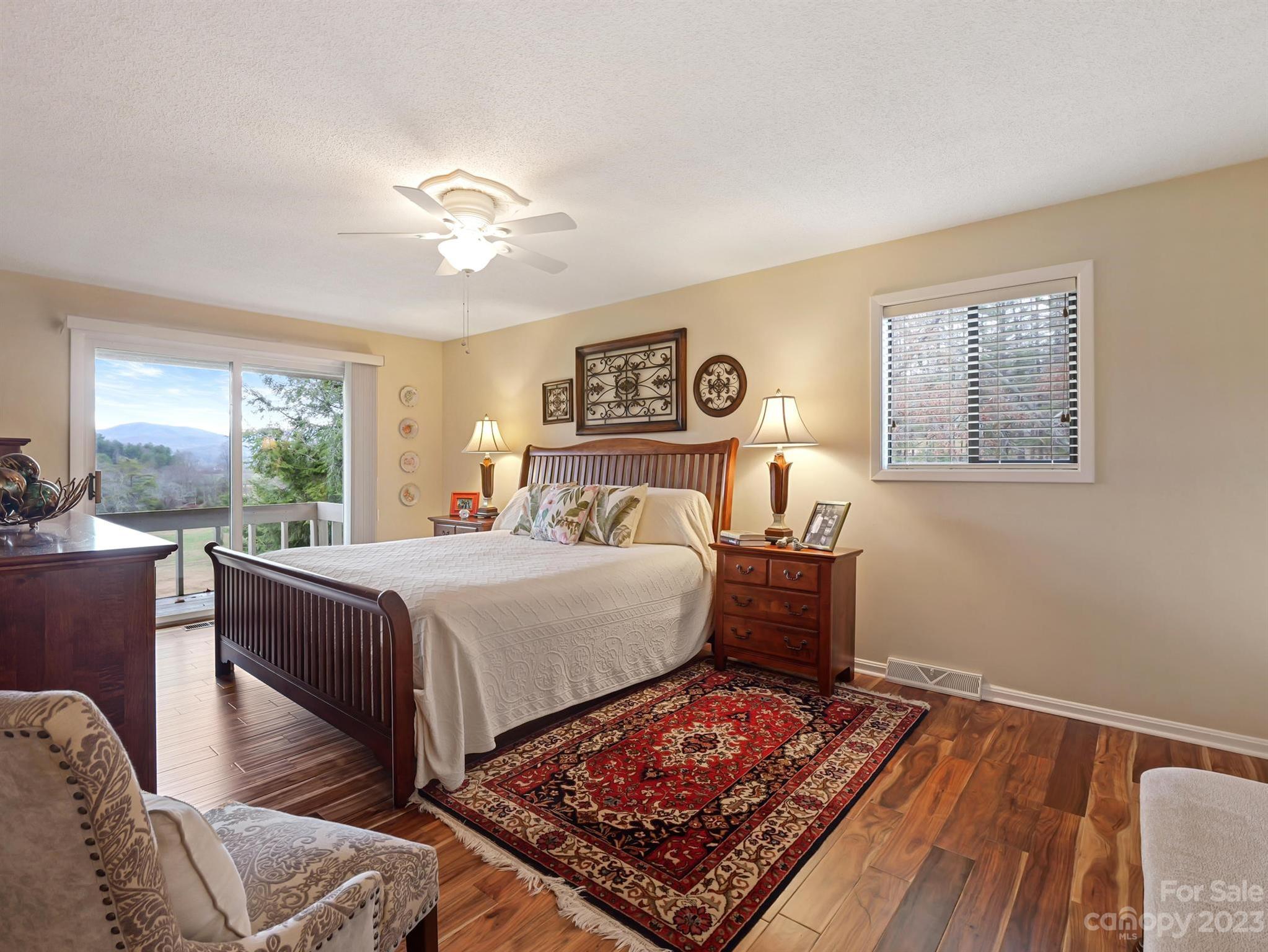 Furnished bedroom with a dark wood bed and mountain views through sliding glass doors.