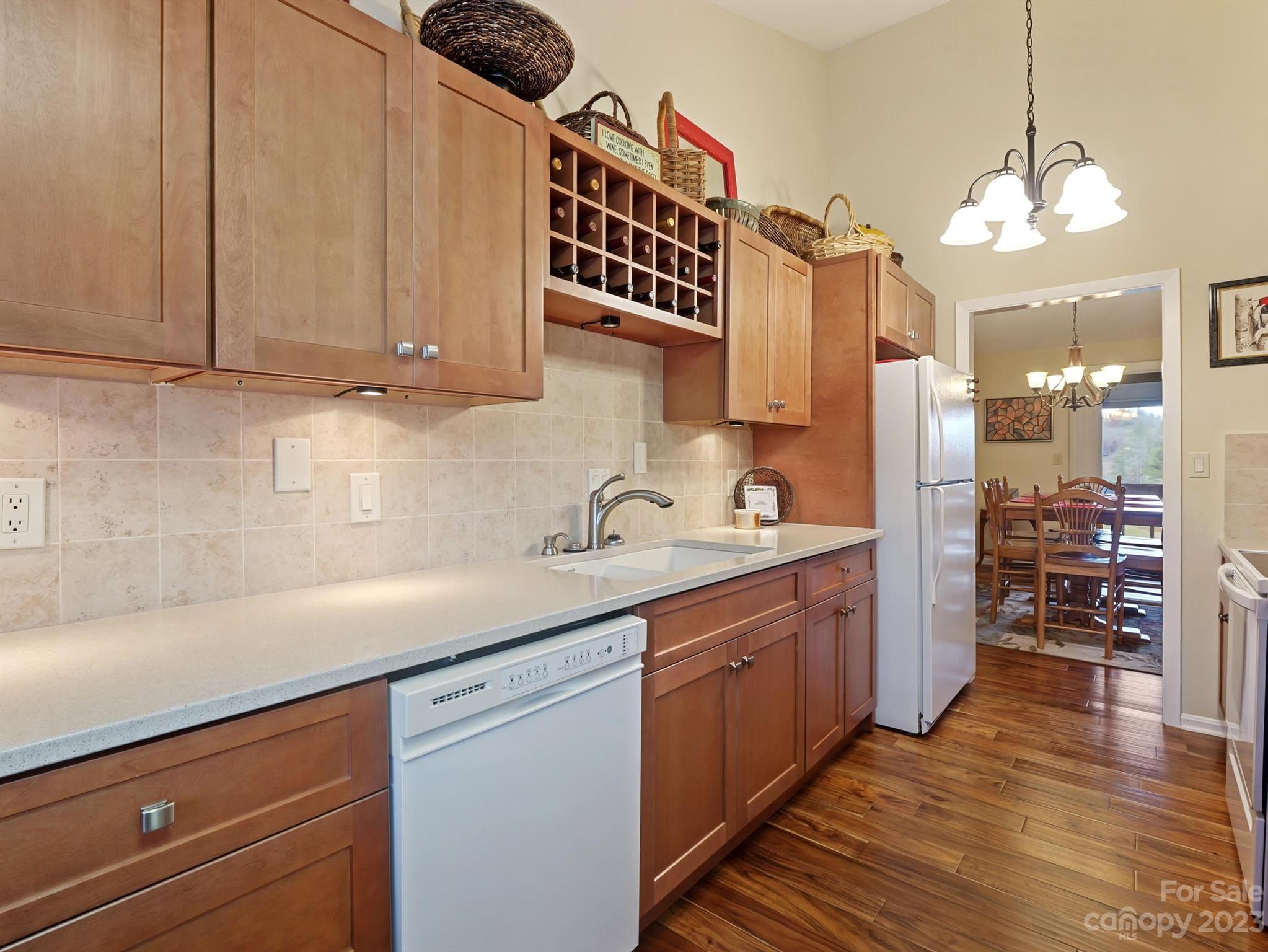 Kitchen with wood cabinets and built-in wine rack, opening to a dining area.