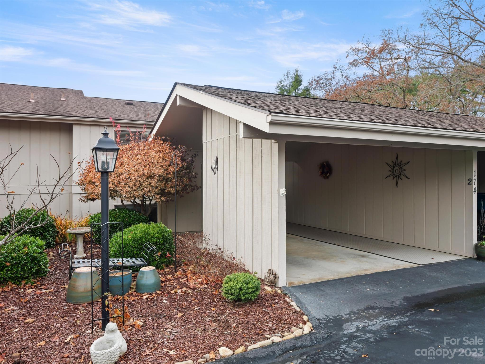 Home exterior with a covered parking bay and landscaped garden with autumn foliage.