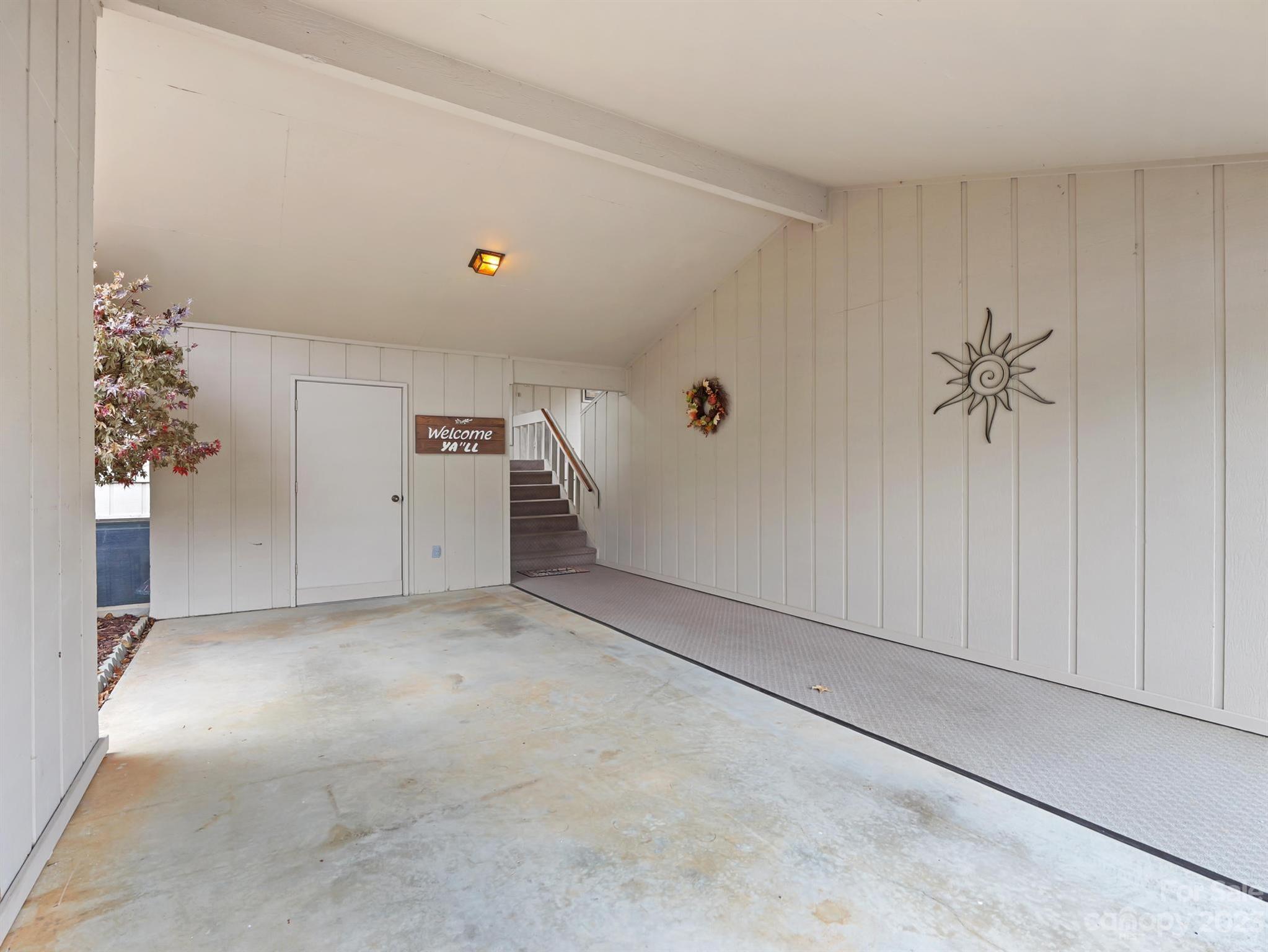 Empty garage with a concrete floor, carpeted parking area, and stairs at the back.