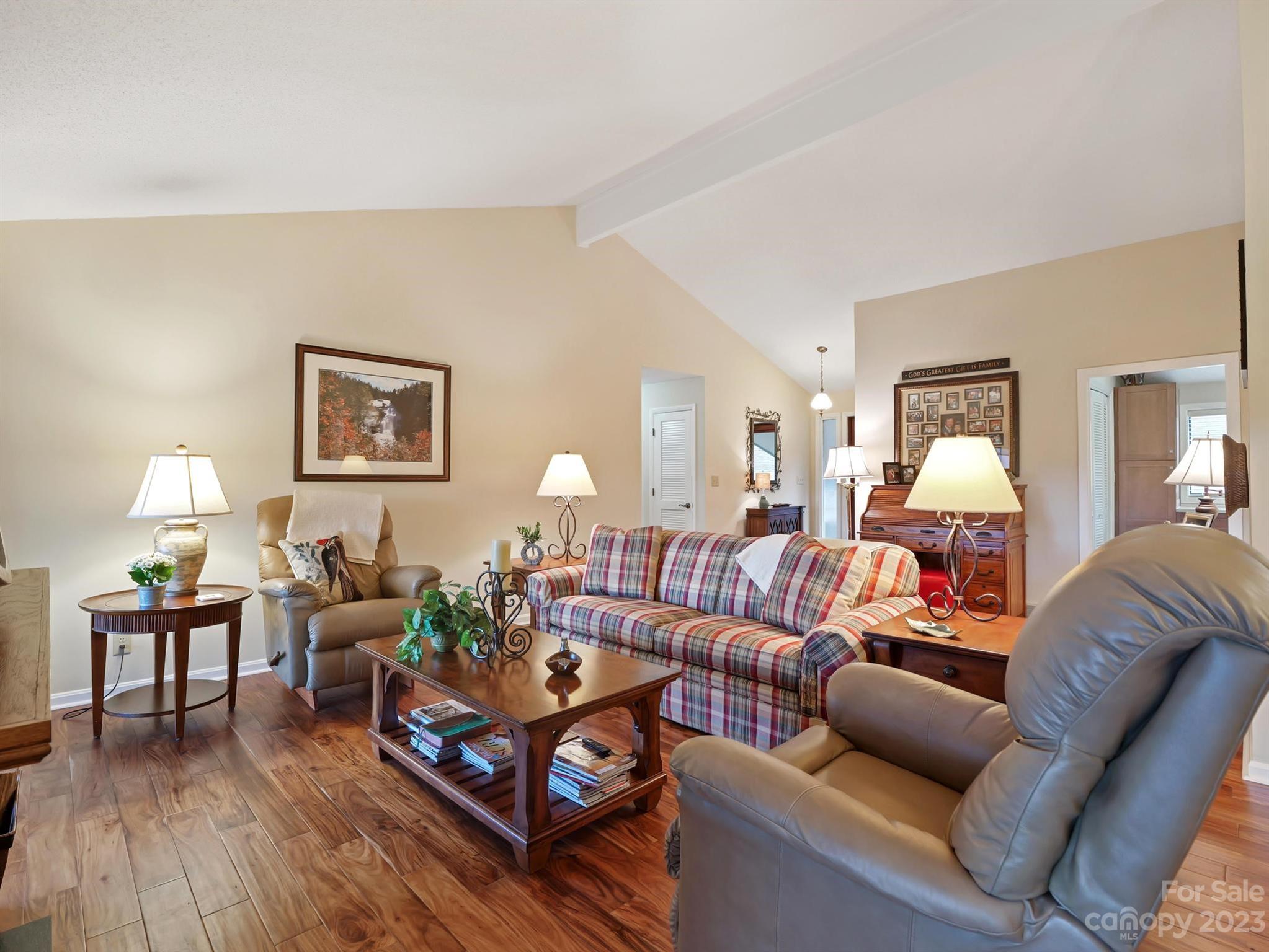 Living room with a plaid sofa, leather recliners, and a wooden coffee table on hardwood flooring.
