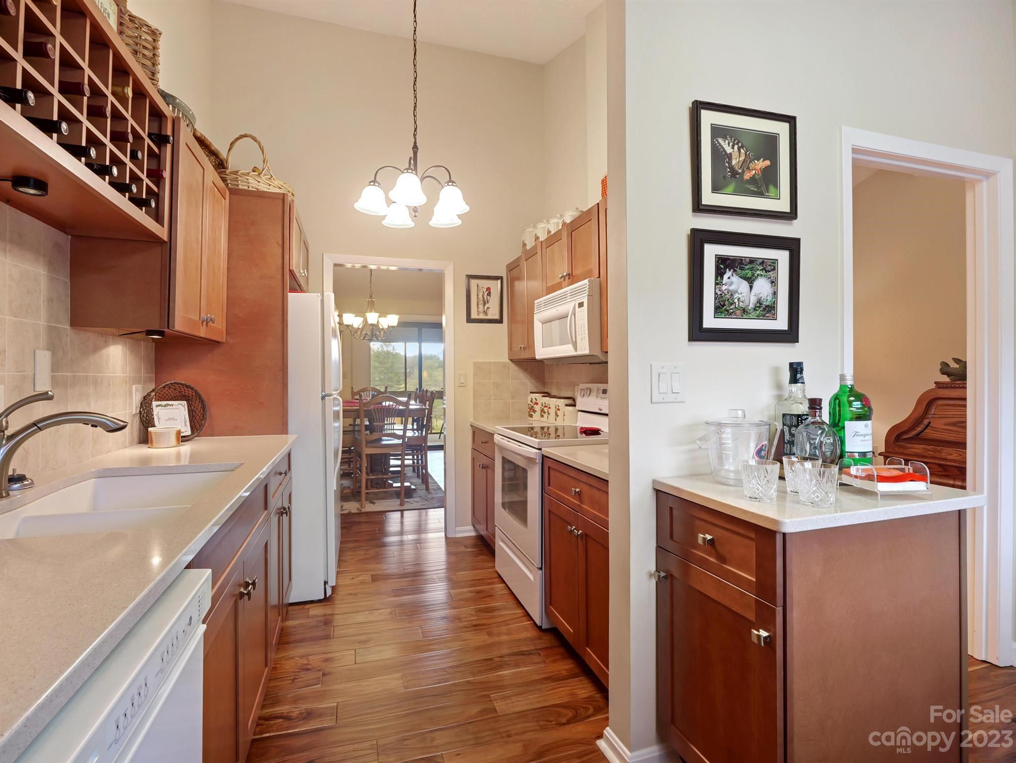 Galley kitchen with warm wood cabinets, a built-in wine rack, and a dining area beyond.