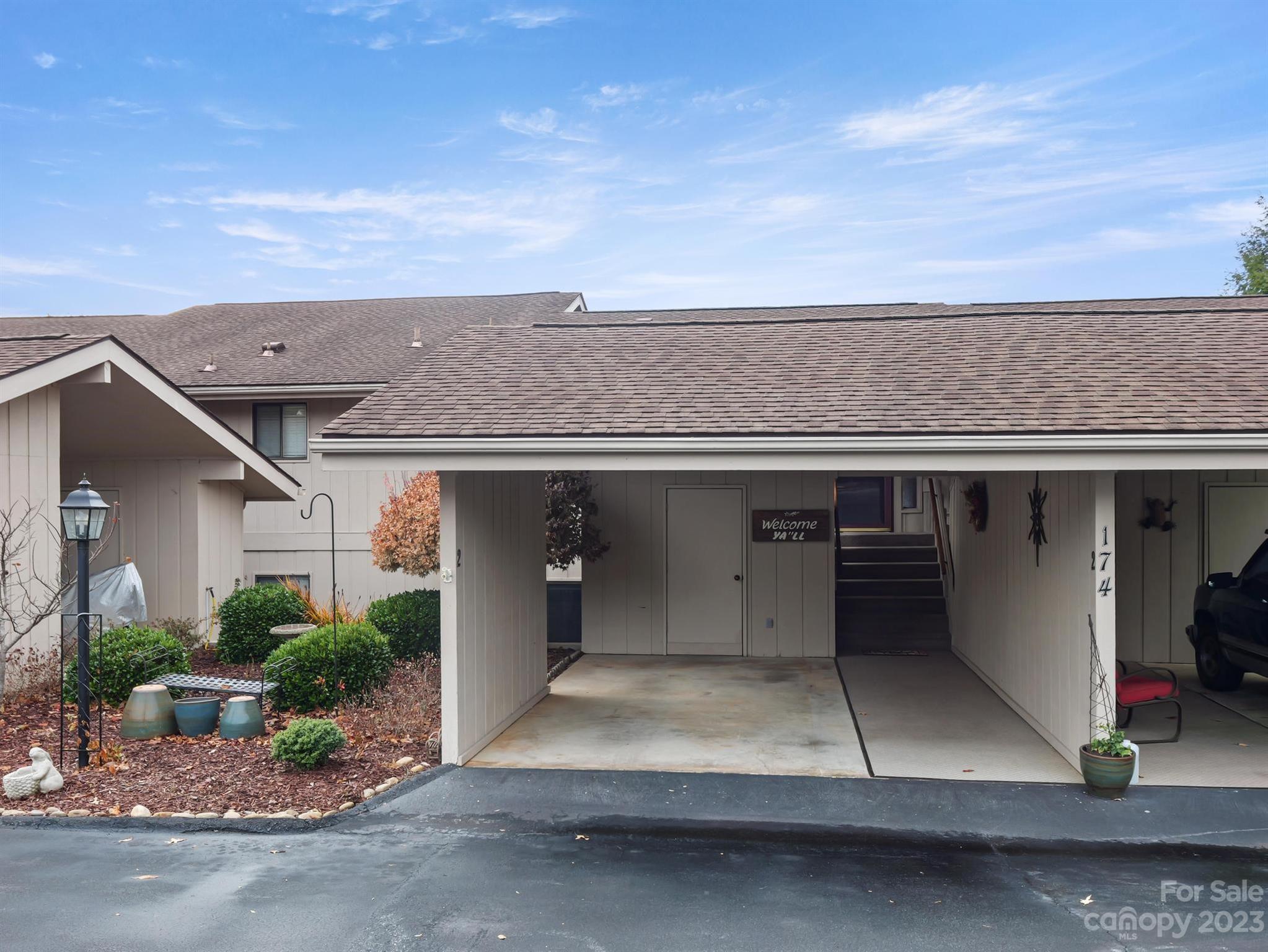 Residence with covered carport, entry stairs, and landscaped garden.