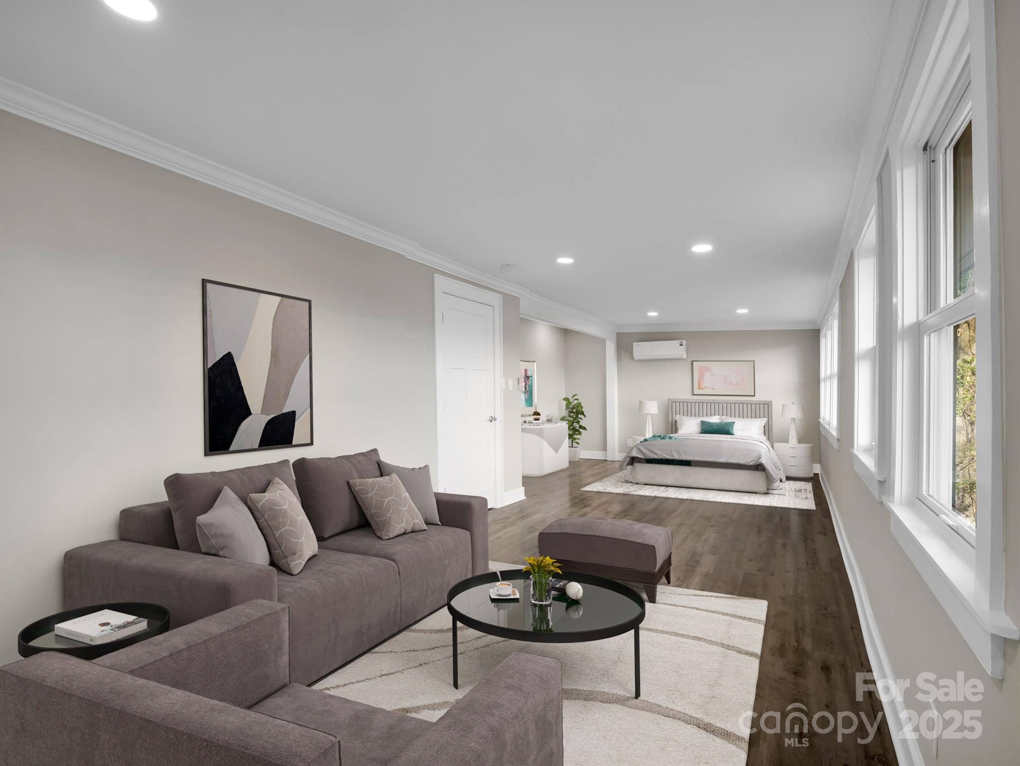 Bedroom suite with a gray sectional, a bed, and large windows along one wall.