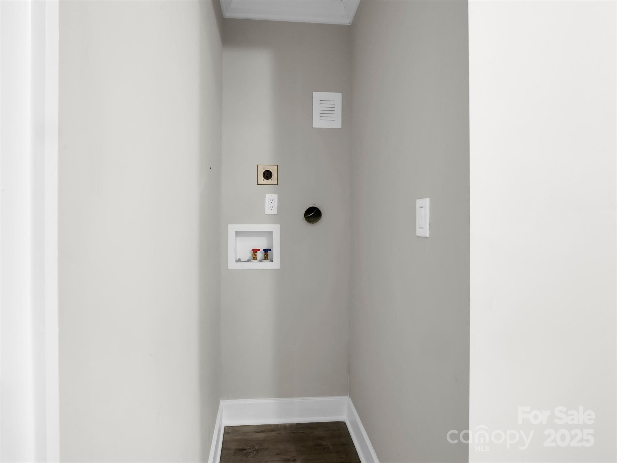 Empty laundry closet with washer and dryer hookups and a wall vent.