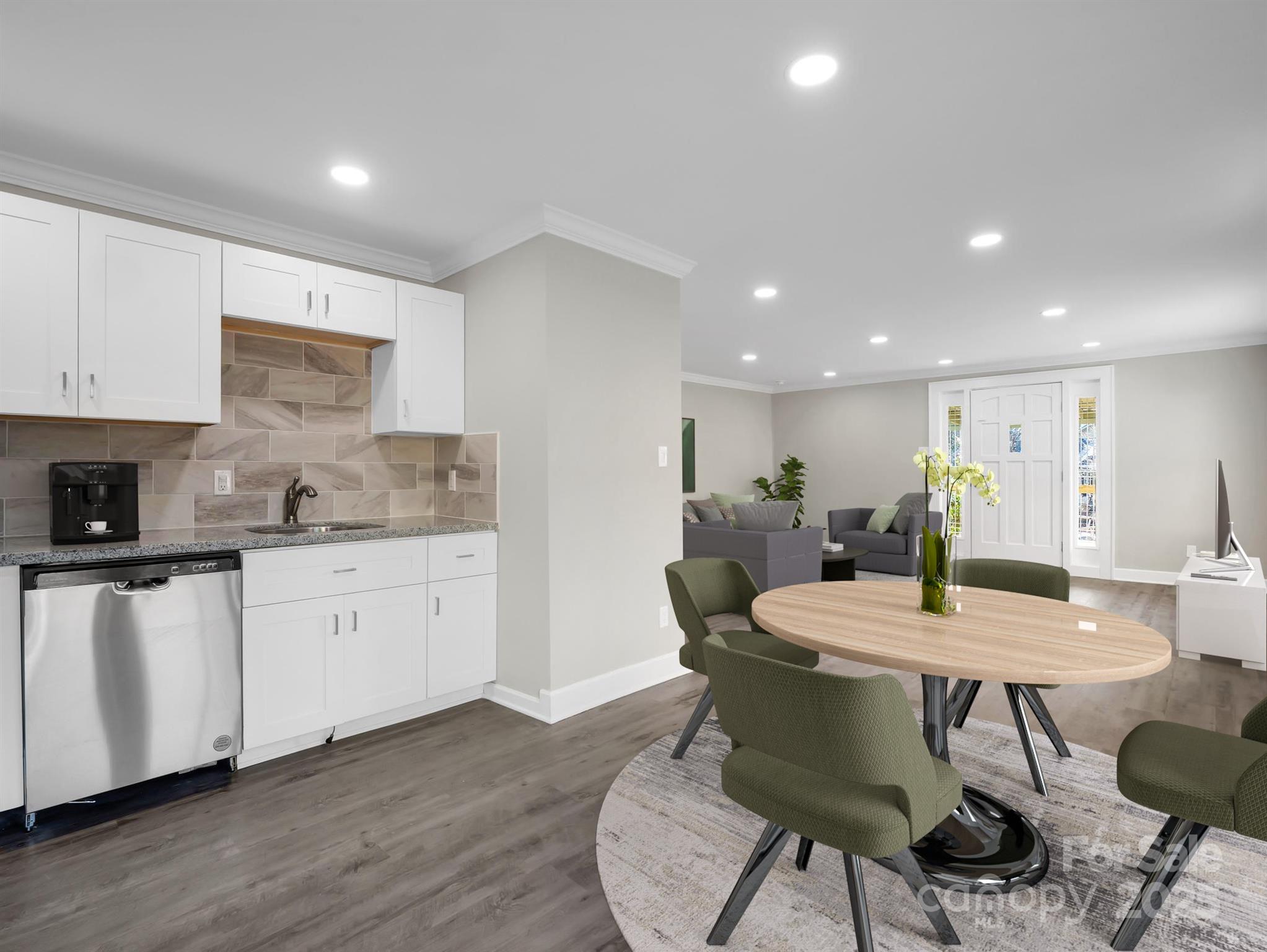 Open-plan kitchen and dining area with white cabinets, a wood dining table, and green chairs.