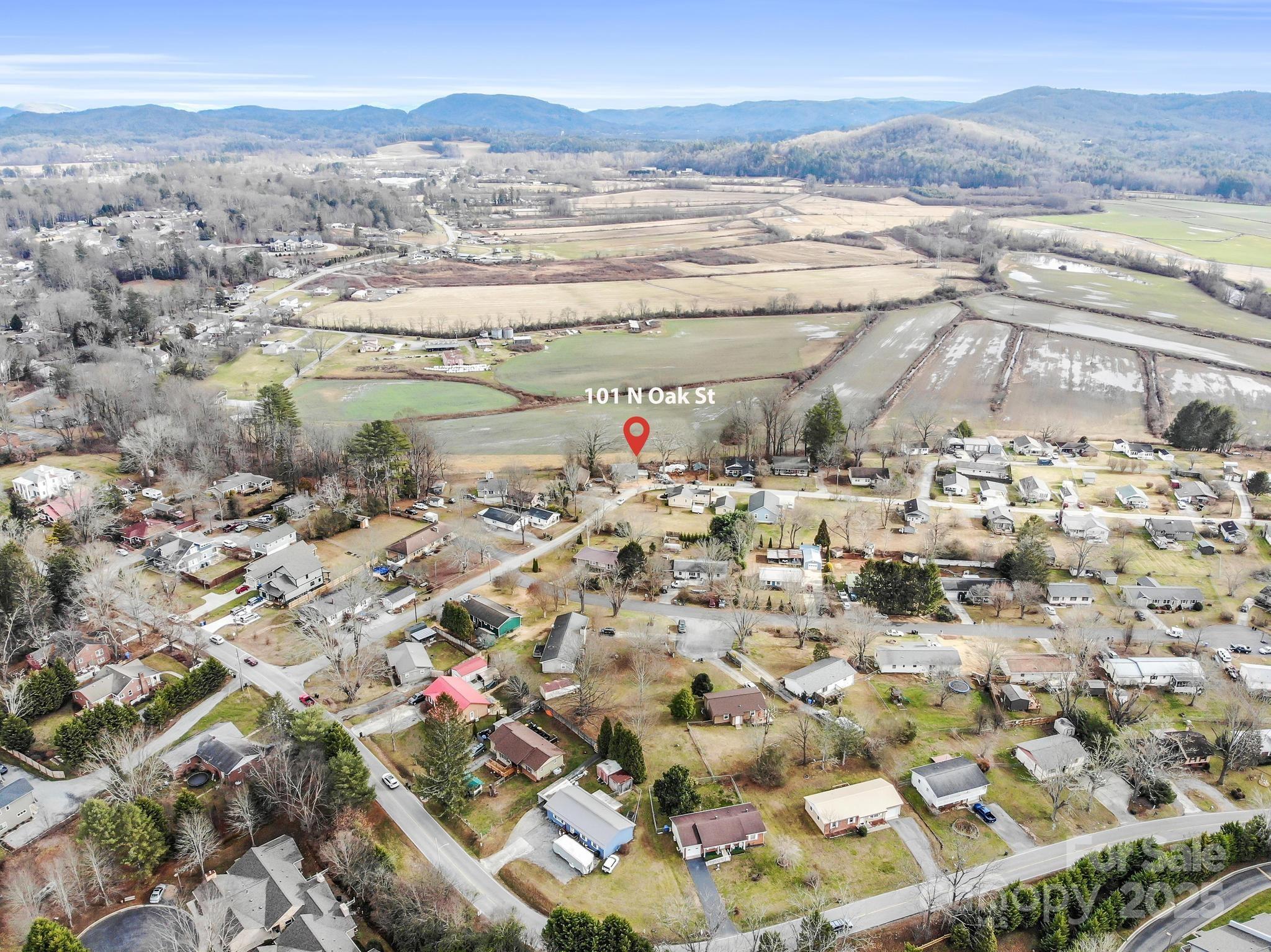 Aerial view of 101 N Oak Street, with surrounding fields, neighborhood homes, and distant mountains.