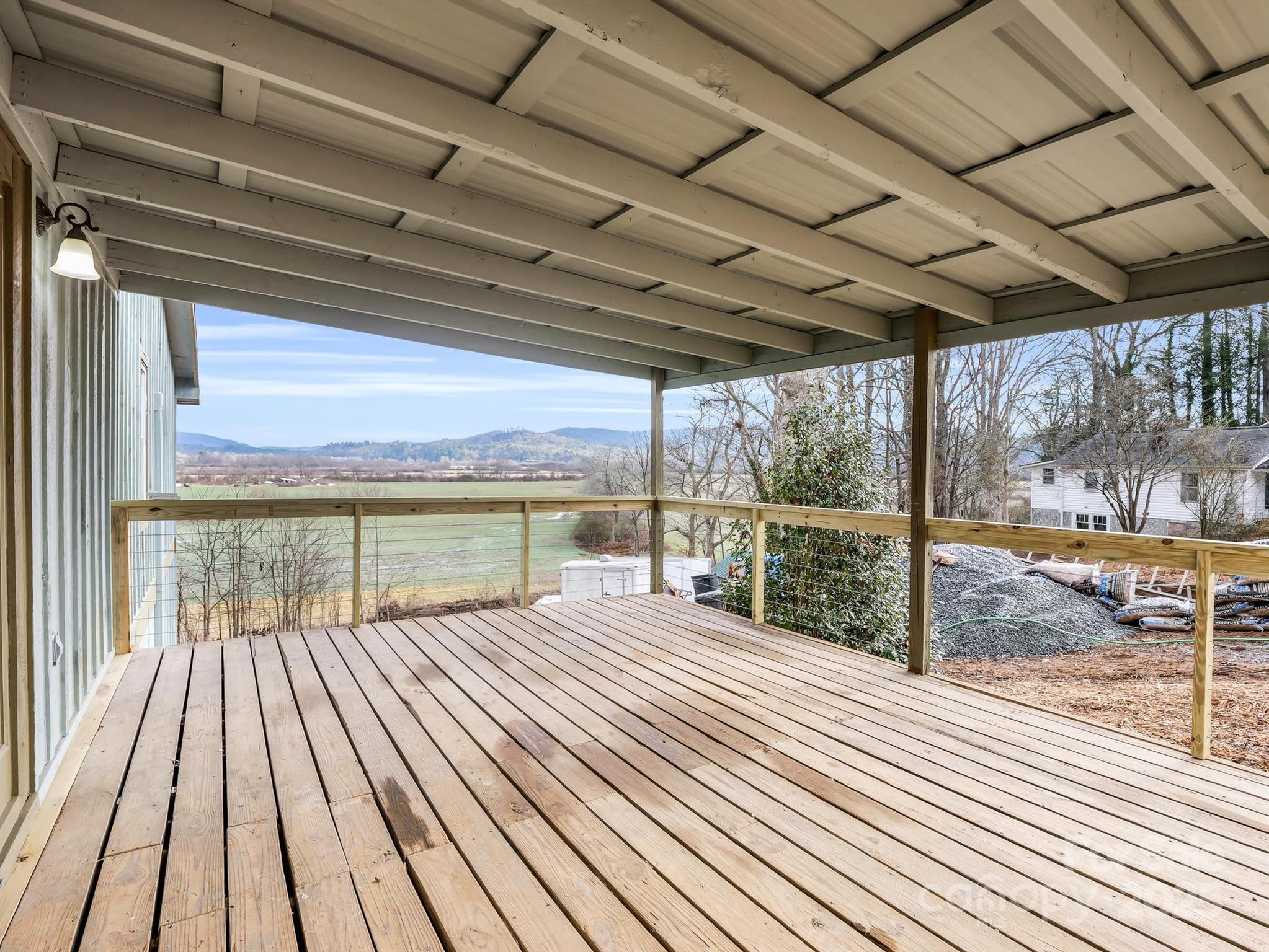 Covered wooden deck overlooking open fields and distant mountain ridges.