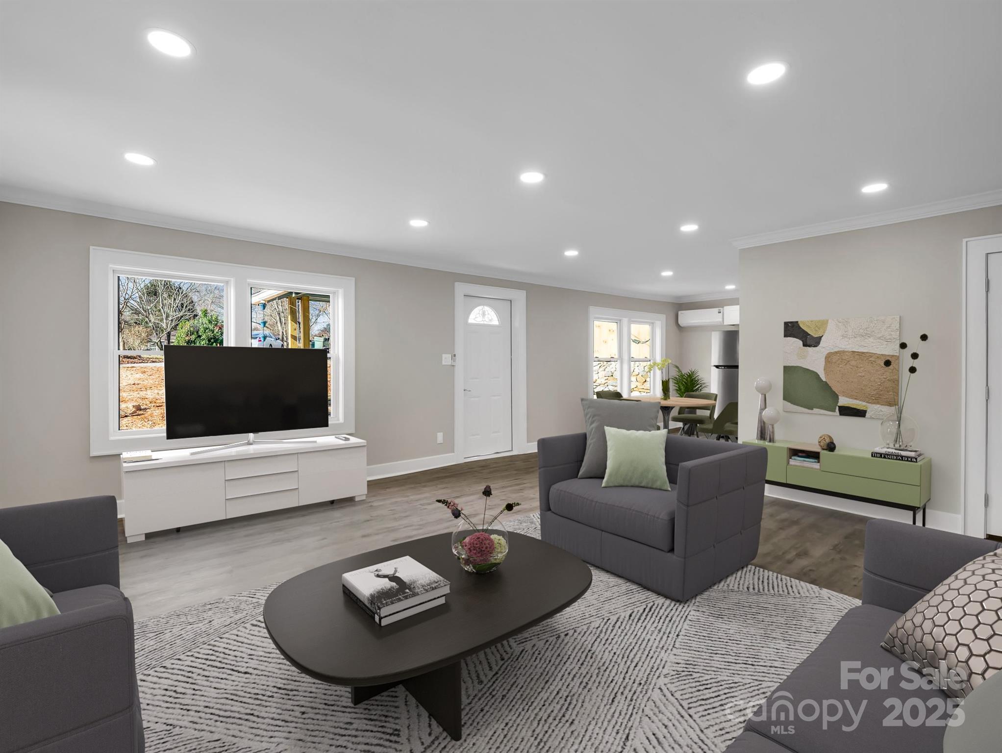 Furnished living room with gray armchairs, a patterned rug, and an adjoining dining area.