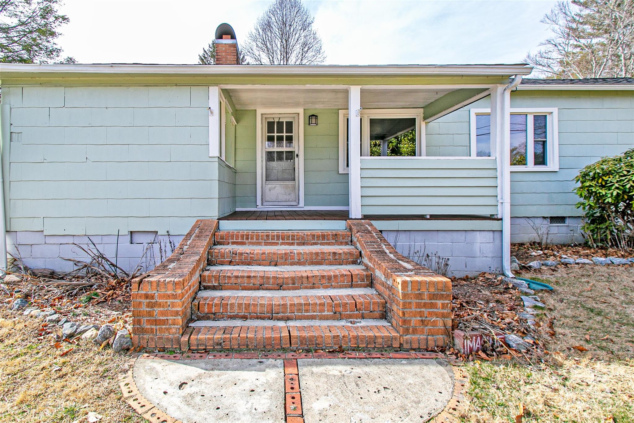 Pale blue house with a covered porch and broad brick steps leading to the front door.