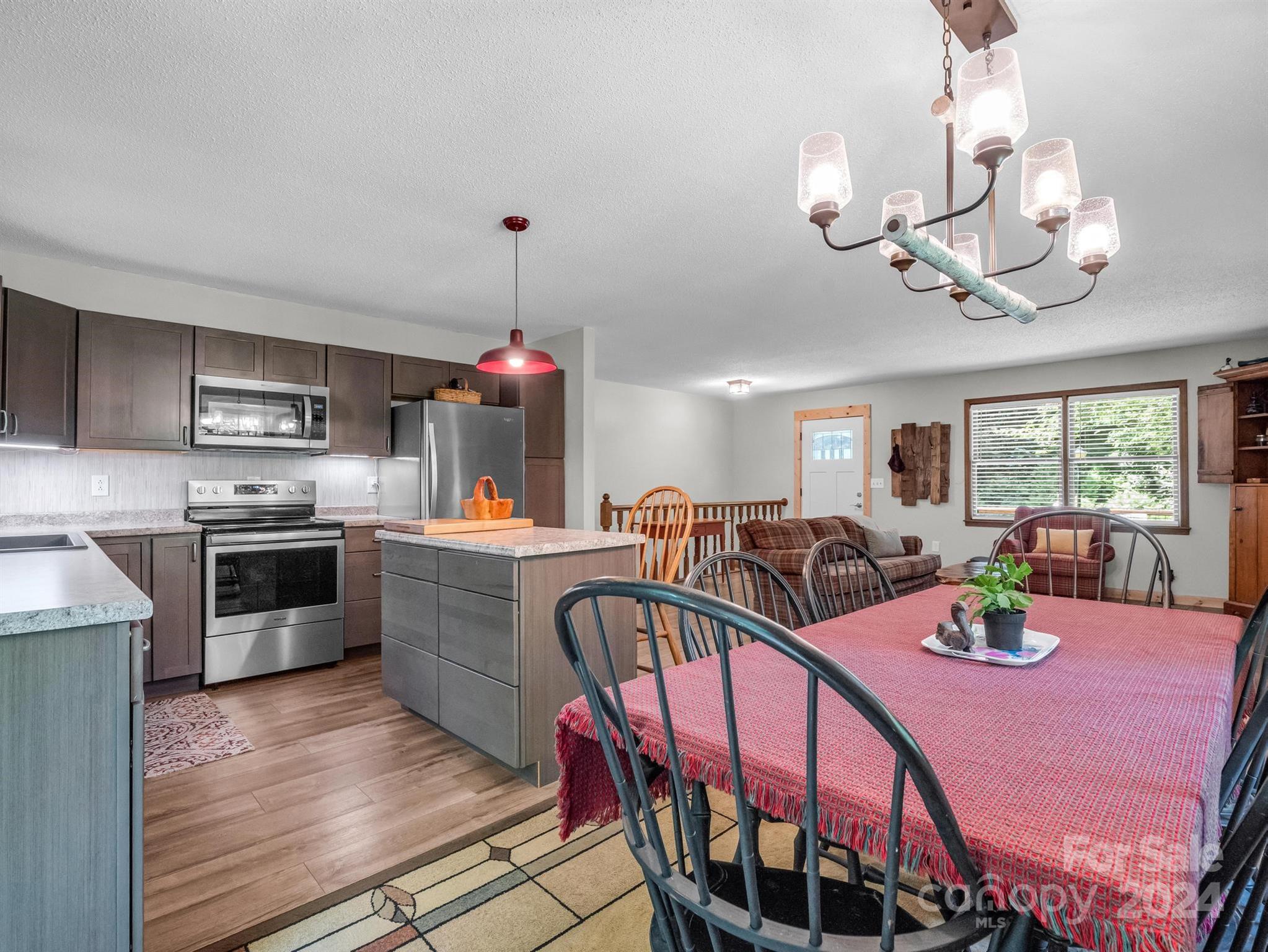 Open-plan kitchen and dining area with dark cabinets, stainless appliances, and a red tablecloth.