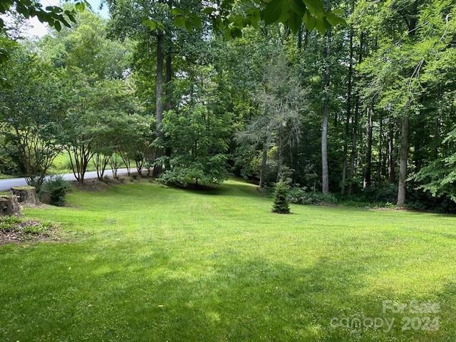 Mowed lawn bordered by mature trees and woodland.