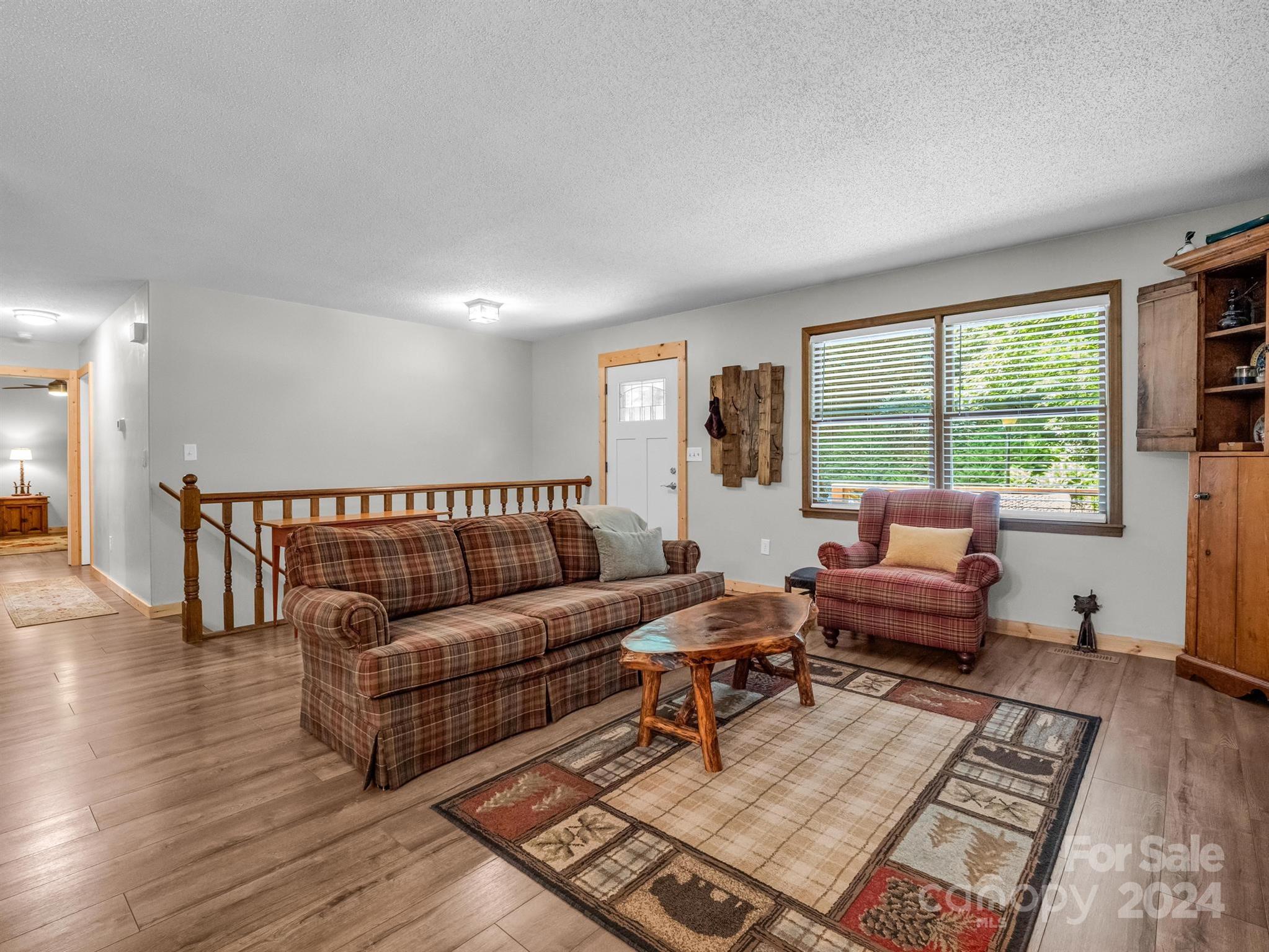 Living room with plaid seating, a live-edge coffee table, patterned rug, and large windows.