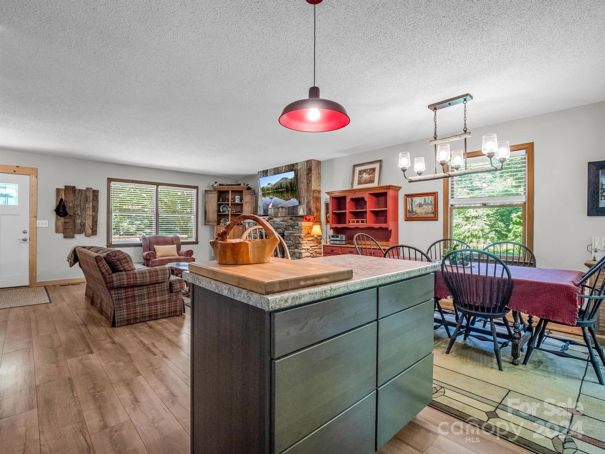 Open-plan kitchen and dining area with a large island, stone fireplace, and red hutch.