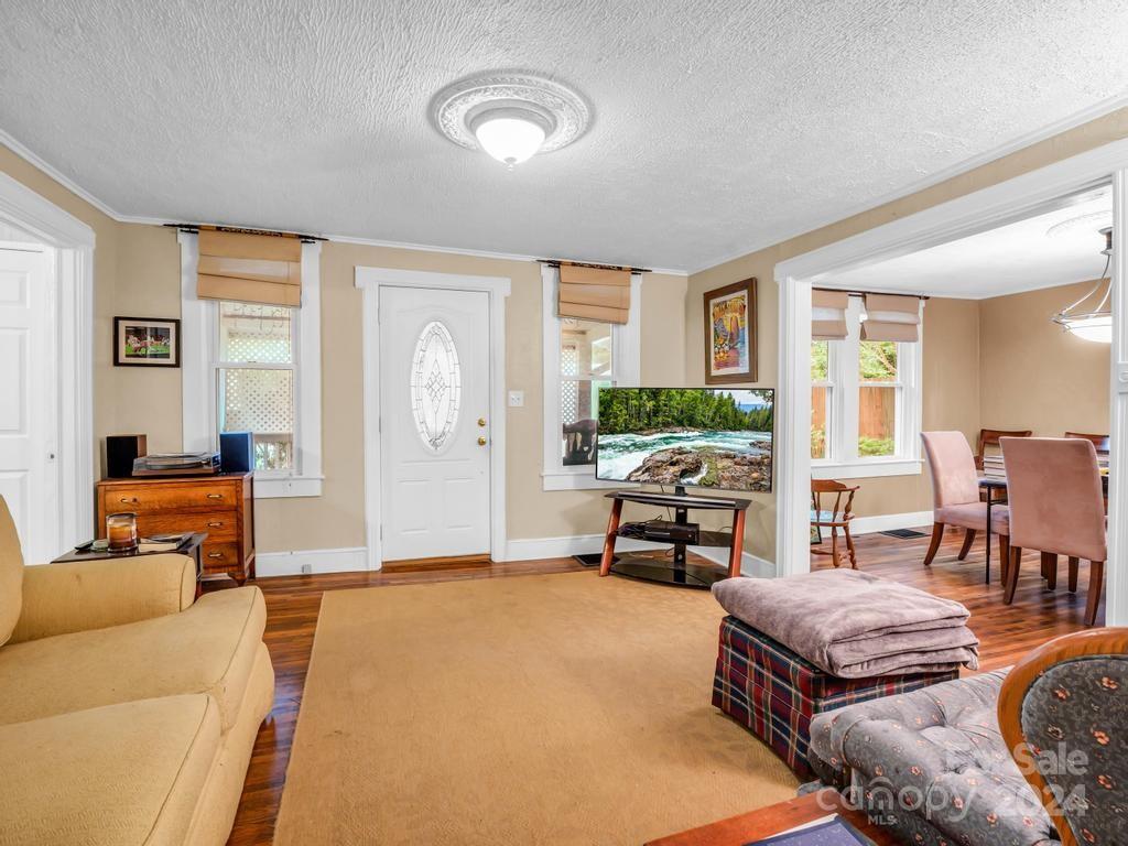 Living room with hardwood floors, a white front door, and an adjoining dining room.