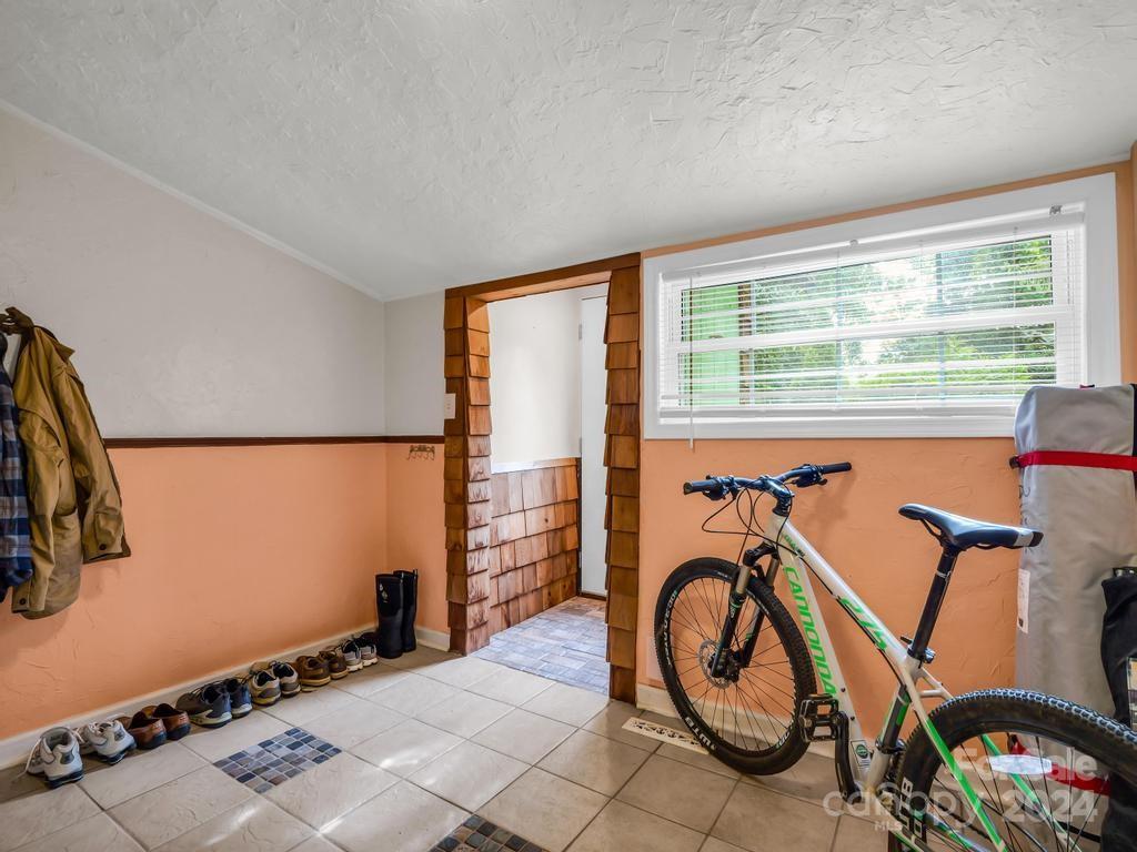 Mudroom with tiled floor, shoes, a bicycle, and a wide window with blinds.