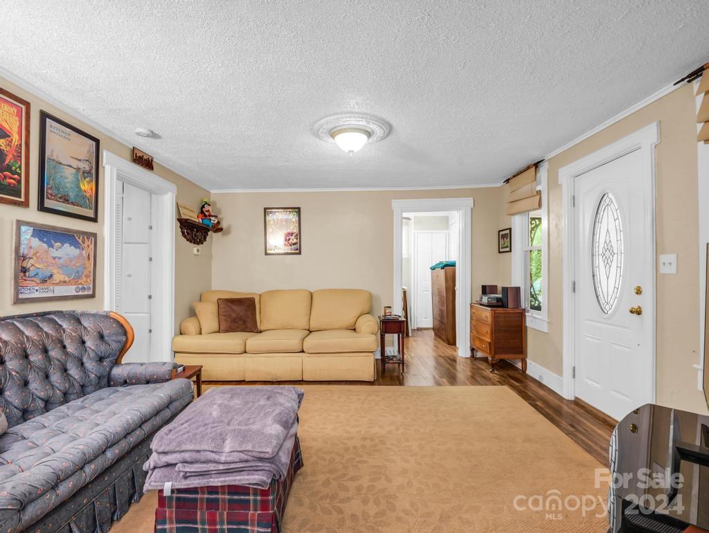 Living room with tan sofa, blue patterned seating, and a white glass-paneled entry door.