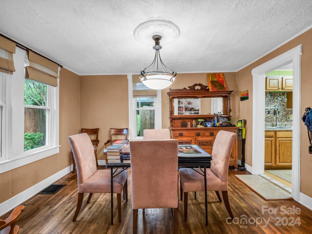 Dining room with pink upholstered chairs, a wooden hutch, and hardwood floors.
