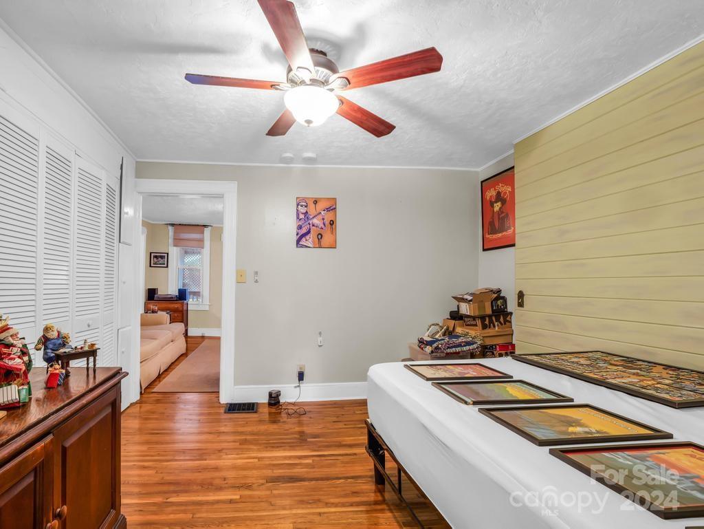 Interior room with hardwood floors, louvered closet doors, and framed artwork displayed on a long table.