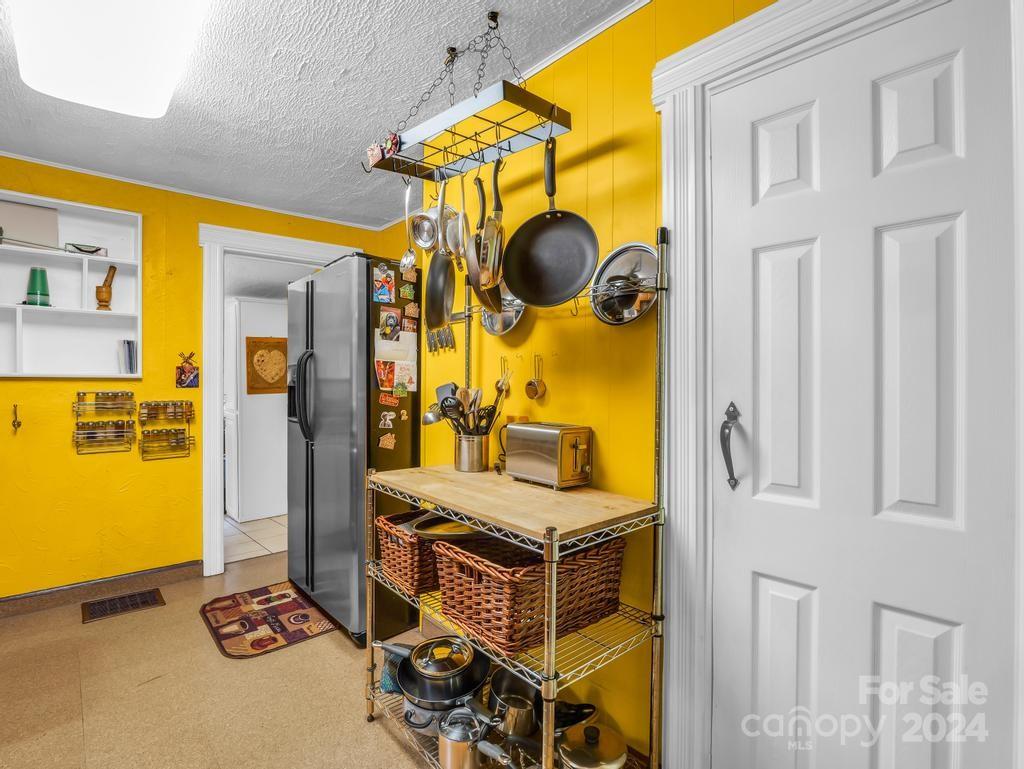 Kitchen with bright yellow walls, hanging cookware, and a stainless-steel refrigerator.
