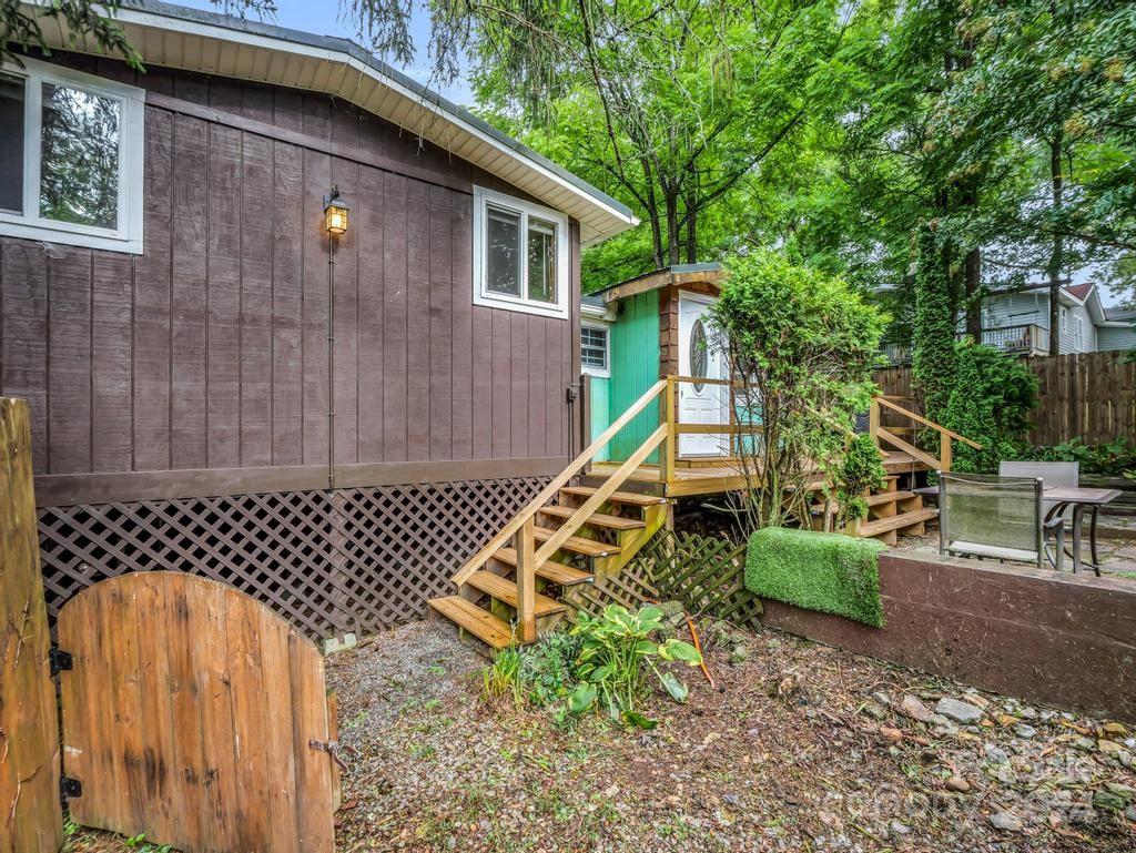 Home exterior with wooden entry stairs, a teal doorway, and a leafy patio area.
