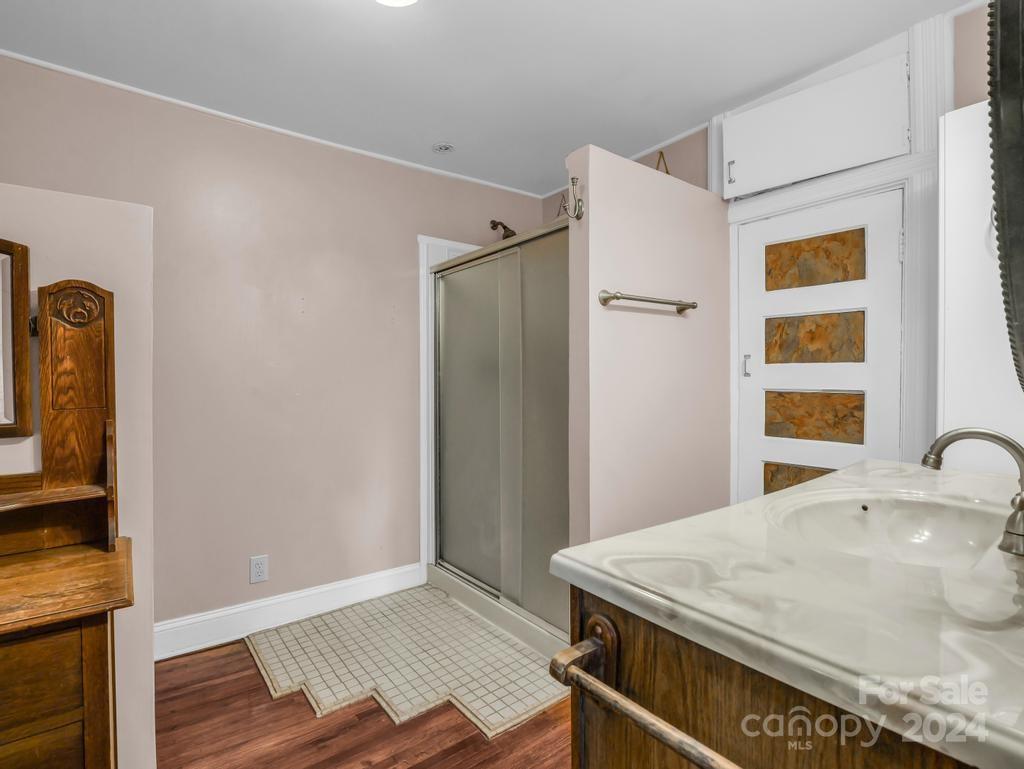 Bathroom with a glass shower, white countertop, dark wood vanity, and tiled floor.