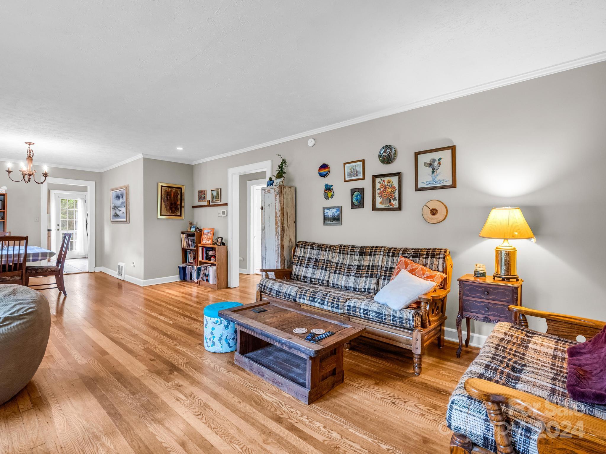 Living room with hardwood floors, a plaid sofa, and a wooden coffee table beneath a gallery wall.