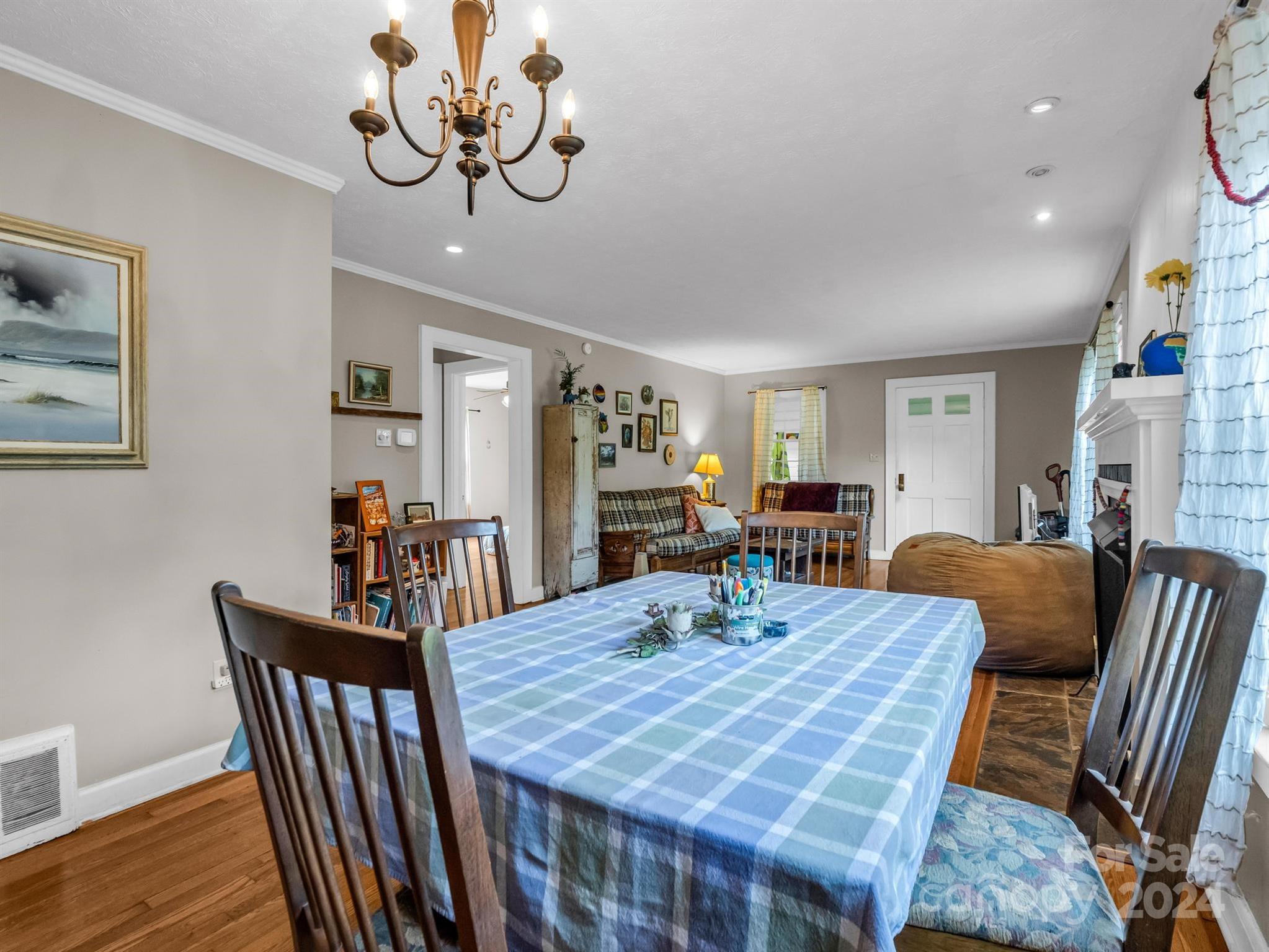 Dining and living room with a blue plaid tablecloth, wood chairs, and a fireplace.