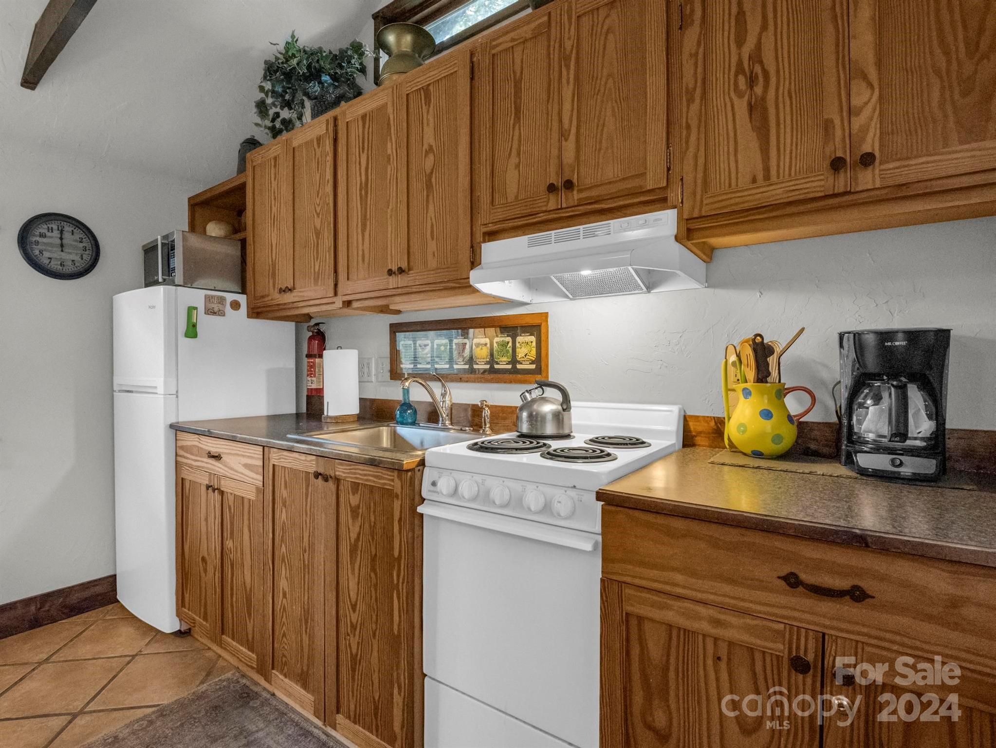Kitchen with wood cabinetry, an electric stove, white refrigerator, and stainless sink.