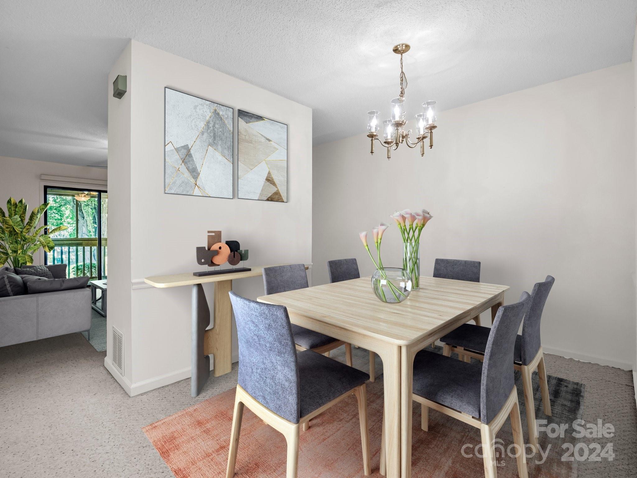 Dining room with a light wood table, gray chairs, brass chandelier, and adjoining living room.