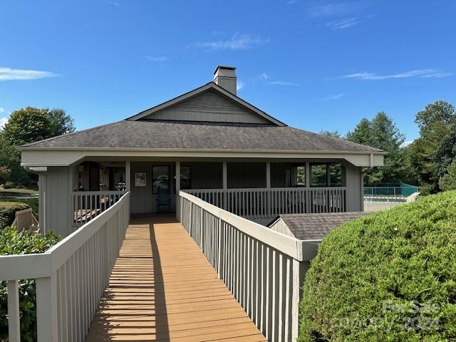 Gray home with a covered porch and a long wooden ramp with white railings.