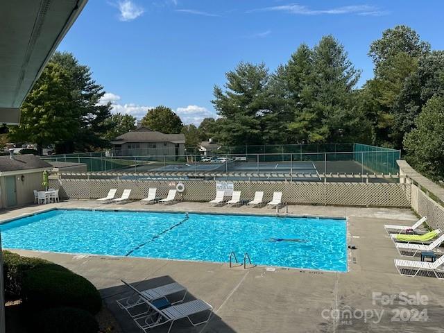 Outdoor swimming pool with blue water, lounge chairs, and a fenced deck.