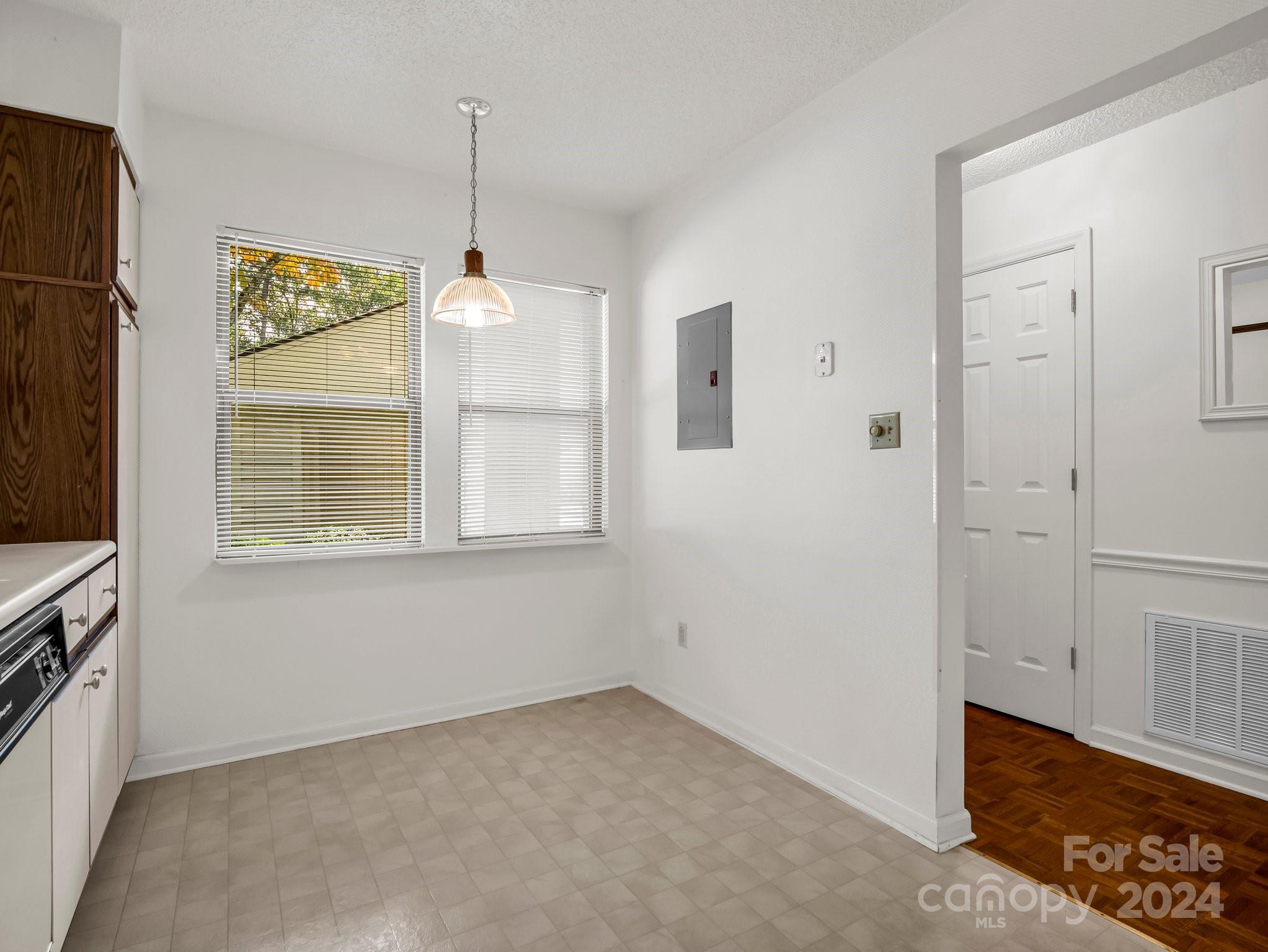 Vacant kitchen with a range, wood upper cabinets, two windows, and light tile flooring.