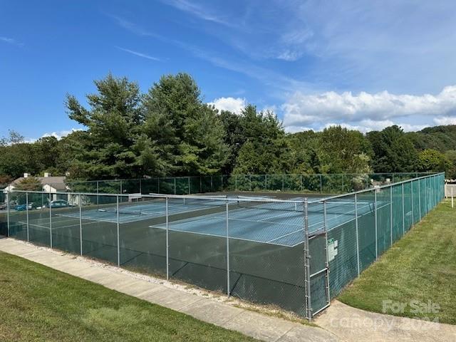 Outdoor tennis courts with blue playing surfaces, chain-link fencing, and mature trees.