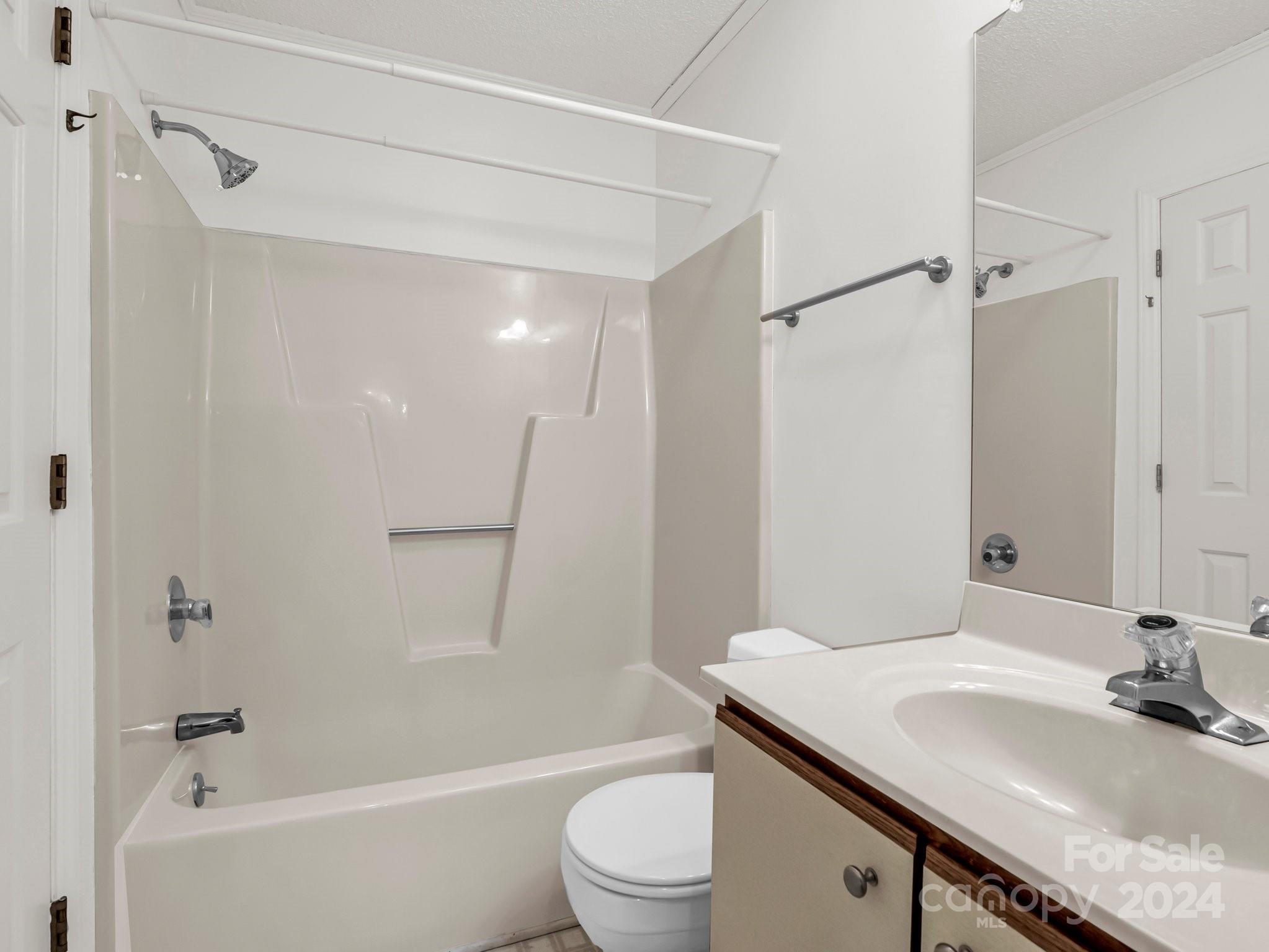 Bathroom with a tub and shower, built-in shelves, and a vanity with sink.
