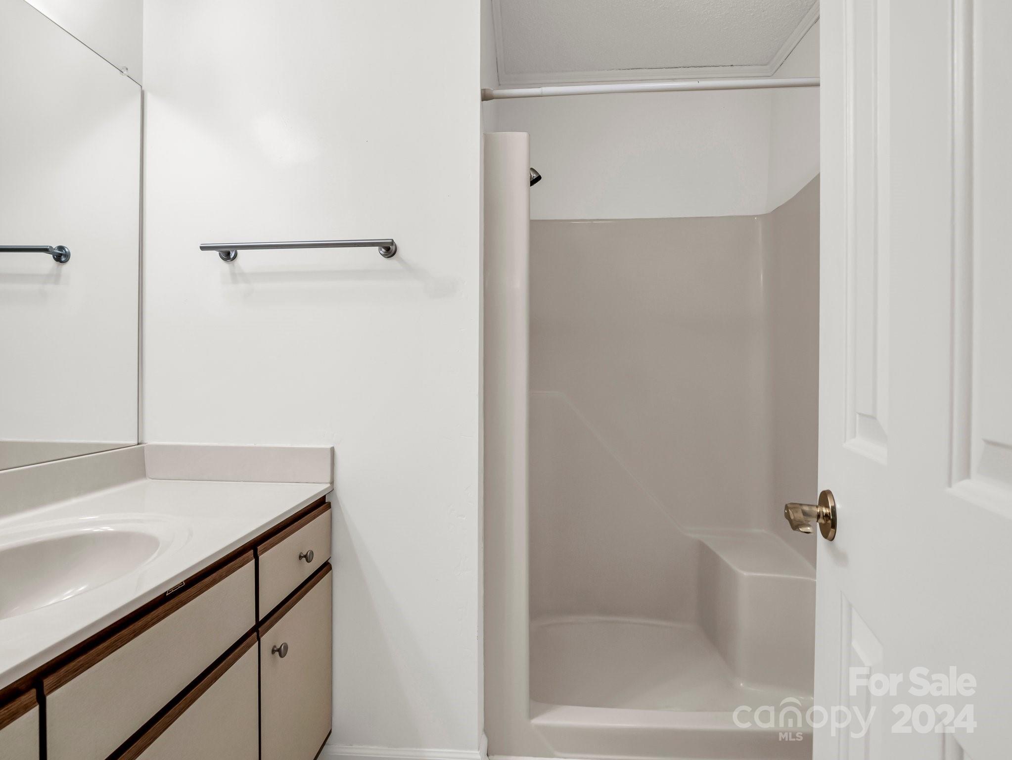 Bathroom with a mirrored vanity and a molded shower stall with built-in seat.